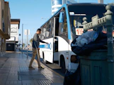 Man with cane boarding a bus on a sunny day.