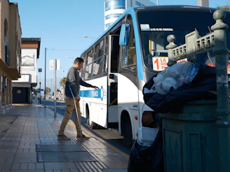 Man with cane boarding a bus on a sunny day.