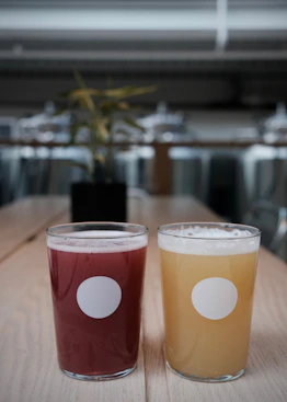 Two glasses of colorful drinks on a wooden table.