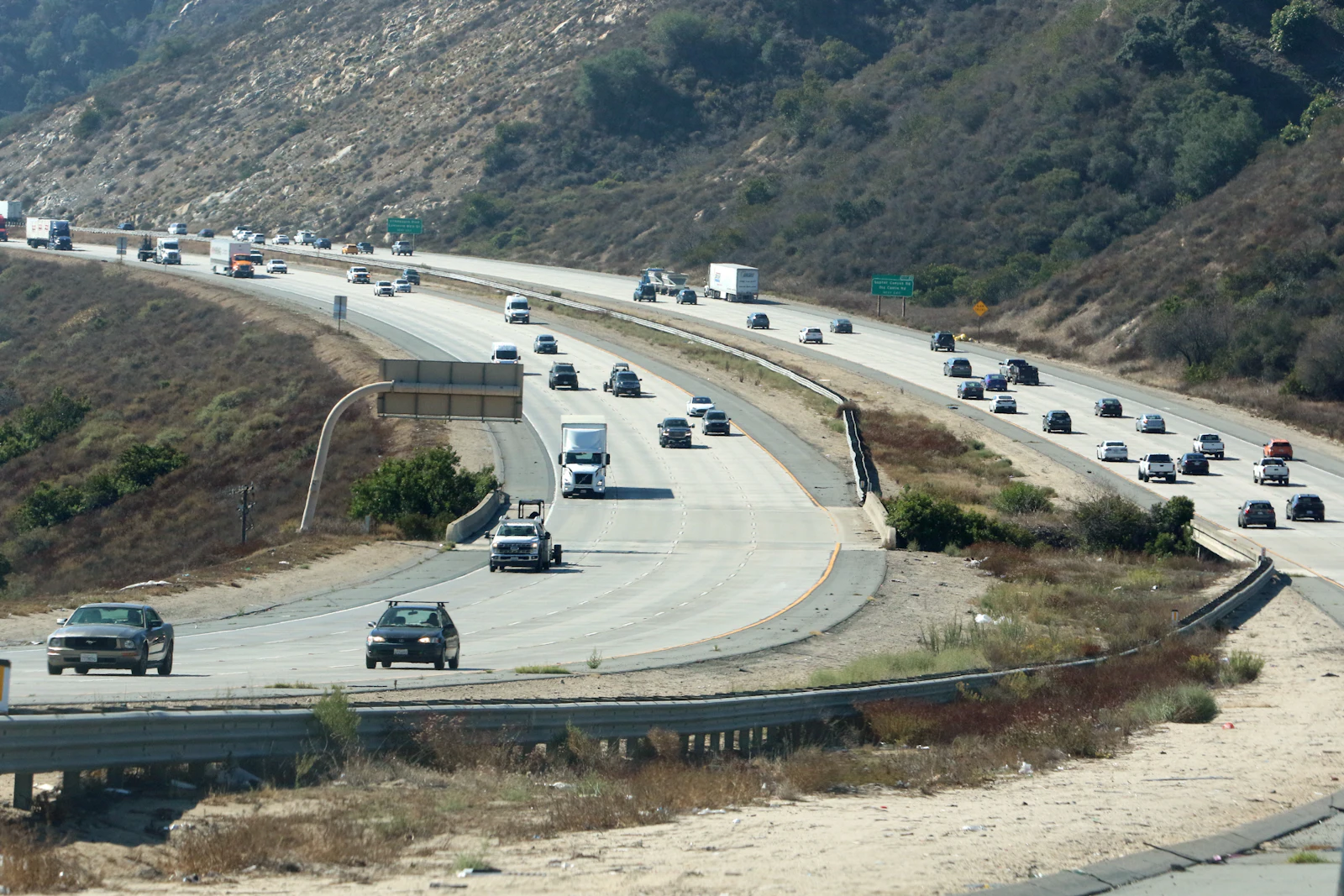 Traffic on a multi-lane highway cutting through hills.