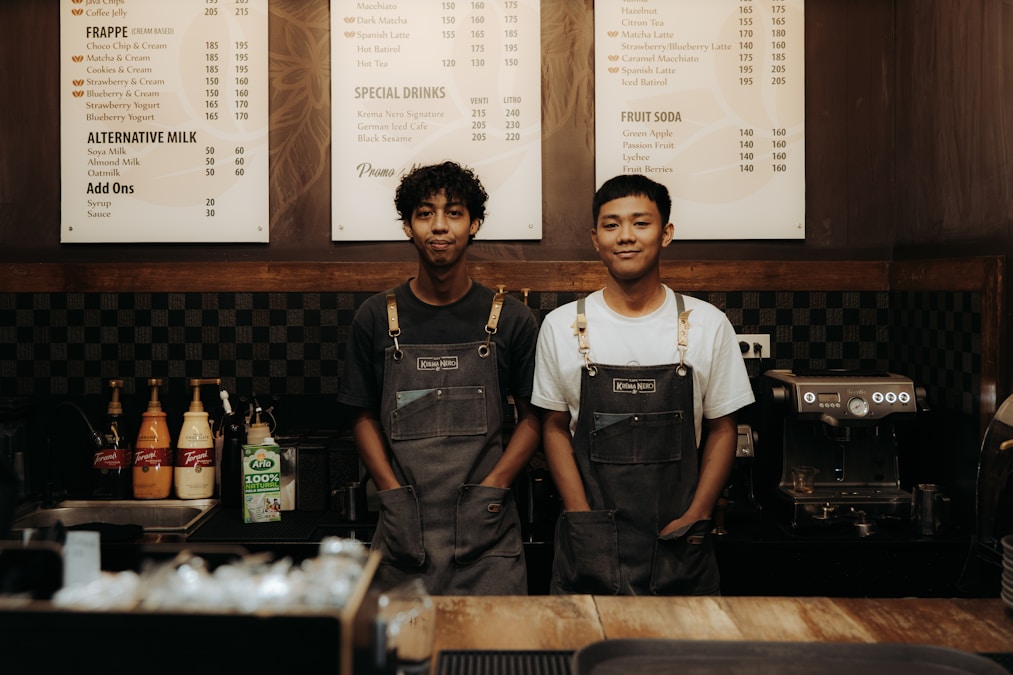 Two baristas smiling behind a coffee shop counter