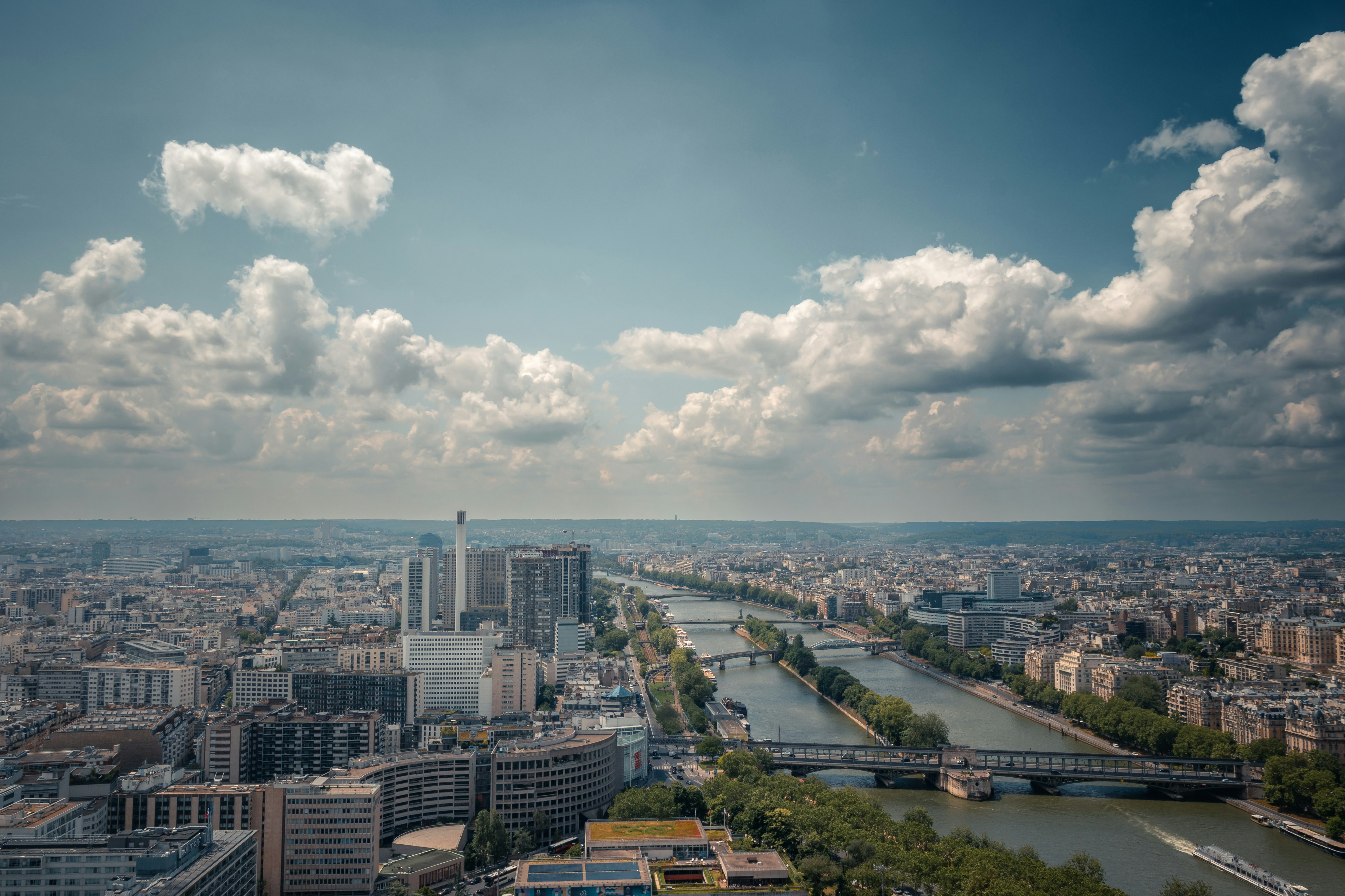 Aerial view of a city with a river and clouds.