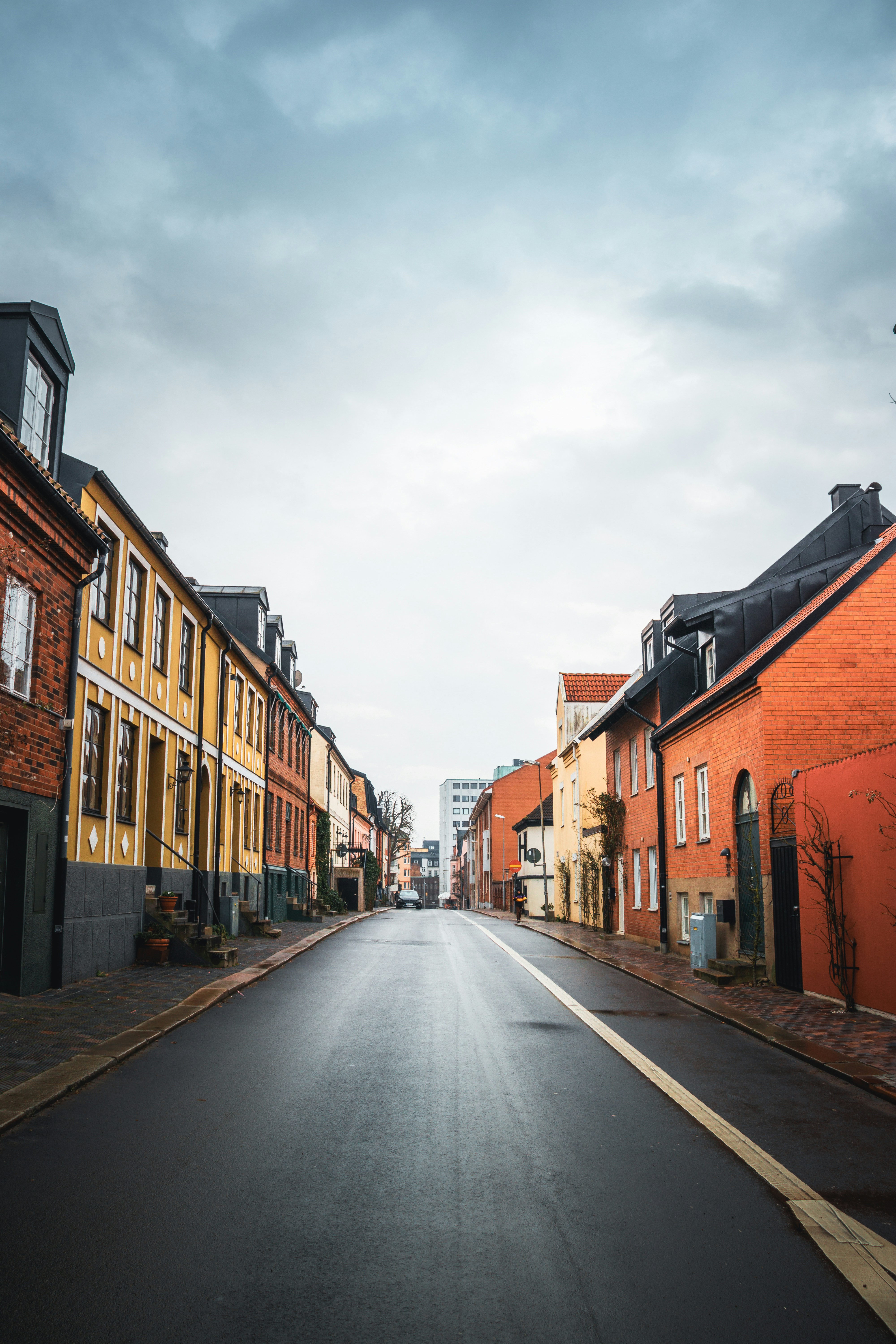 Colorful buildings line a wet street under cloudy sky