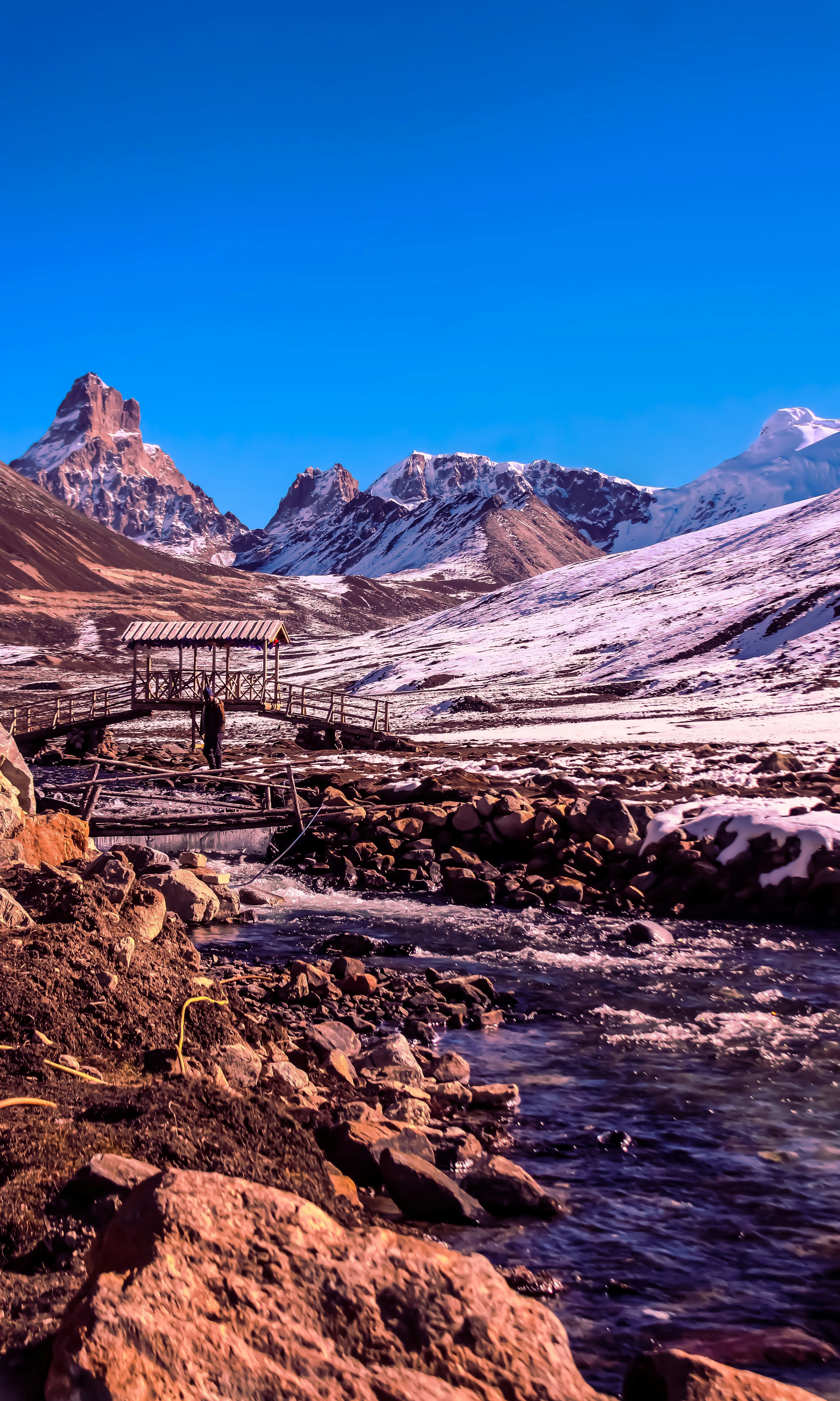 雪山と木製の橋のある川。