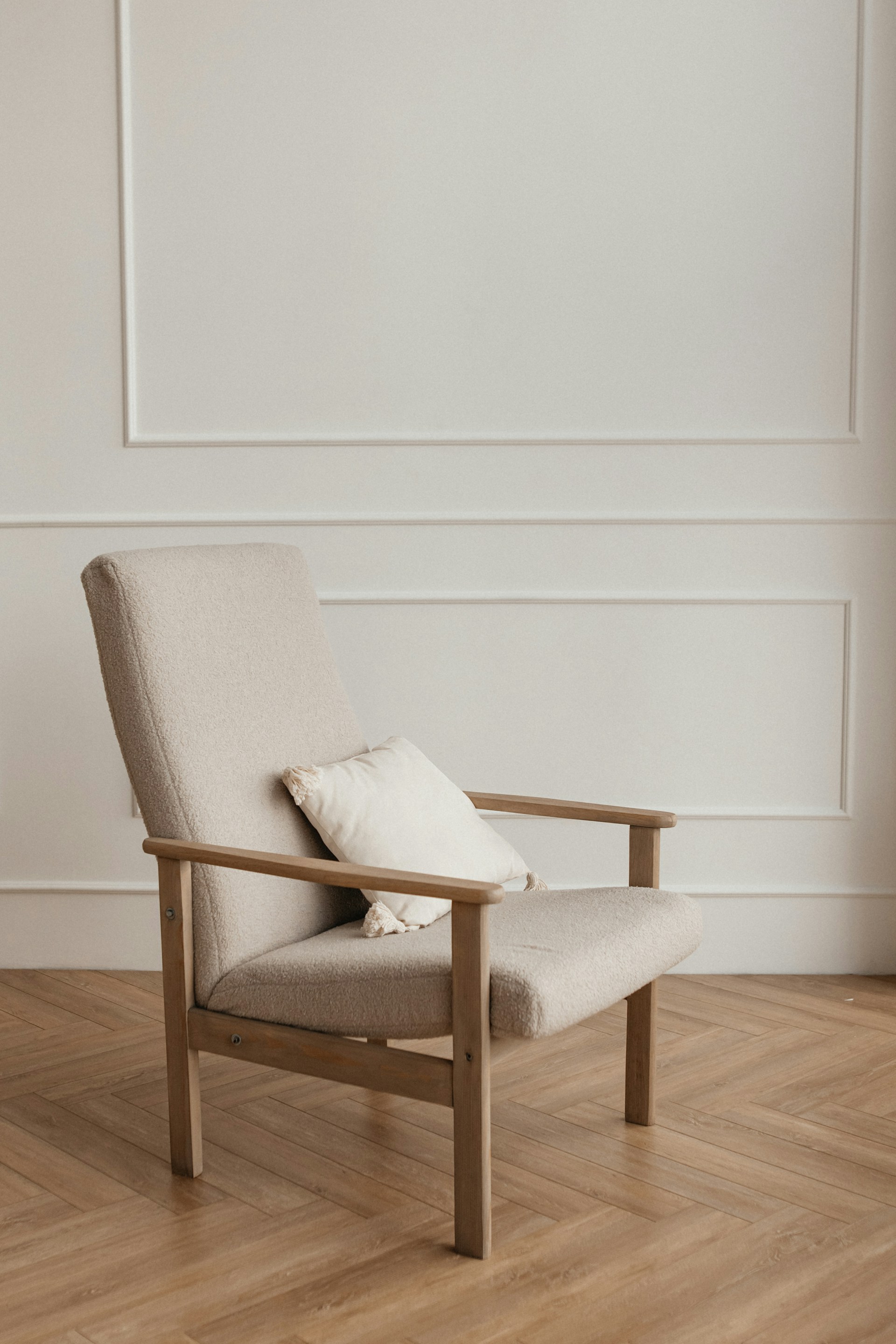 A light-colored armchair with a cushion on wooden floor.