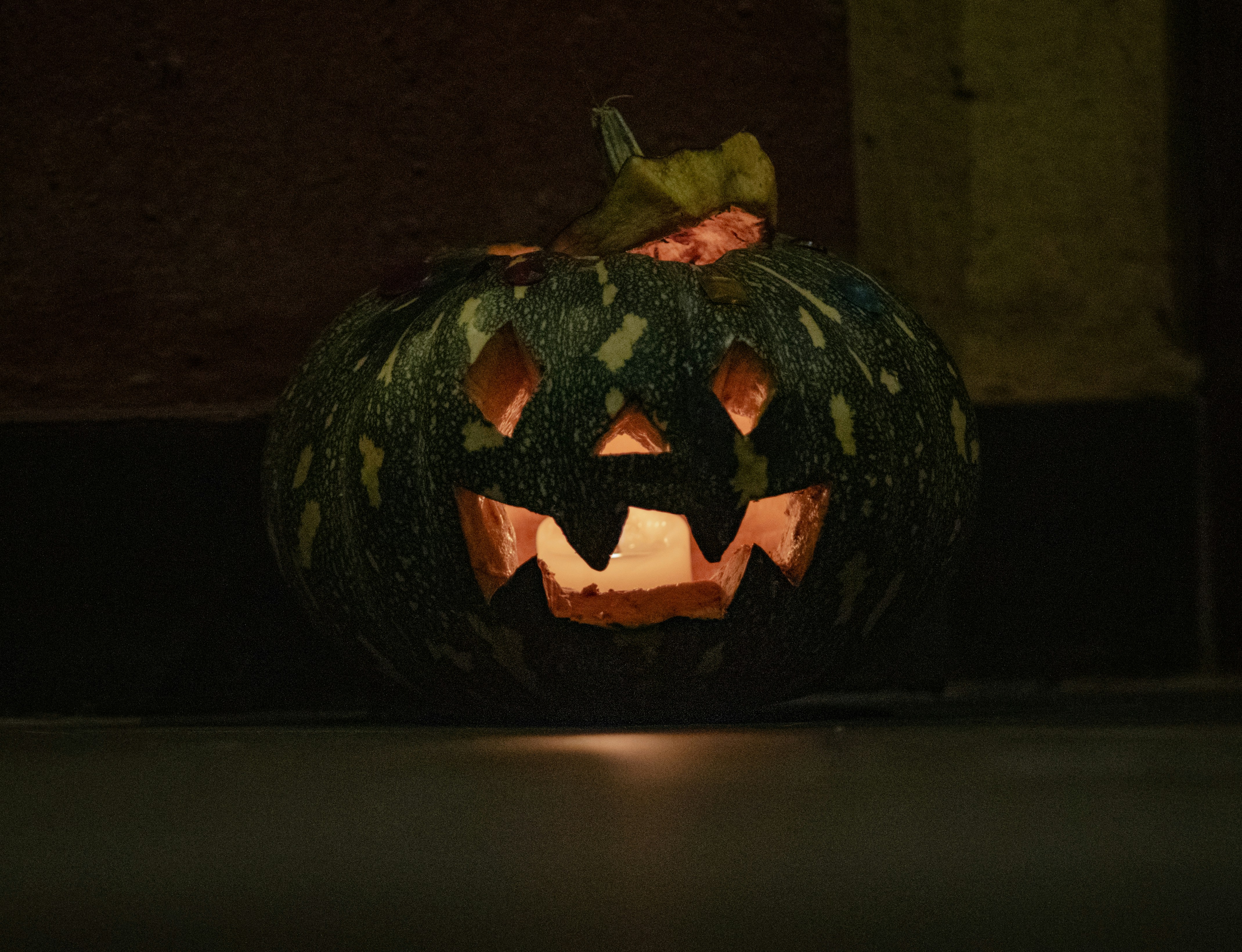 A carved pumpkin with a glowing candle inside at night