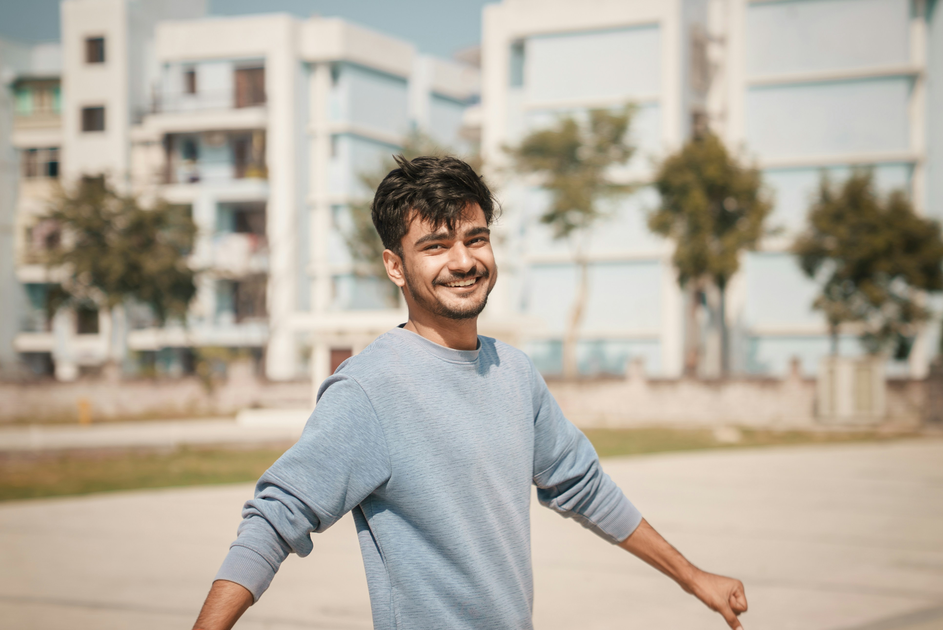 Young man smiling with arms outstretched outdoors