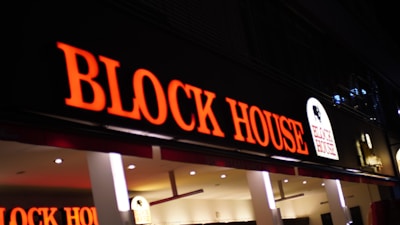 Illuminated sign for block house restaurant at night.