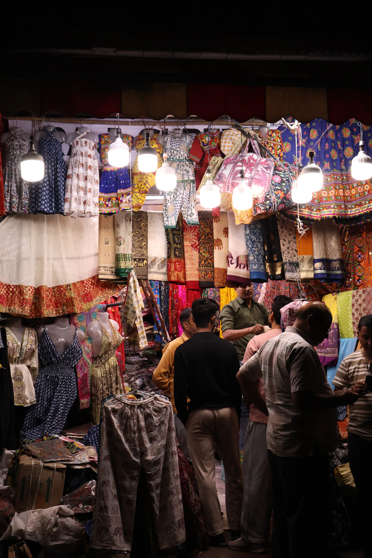 Customers browsing colourful fabrics at a market stall