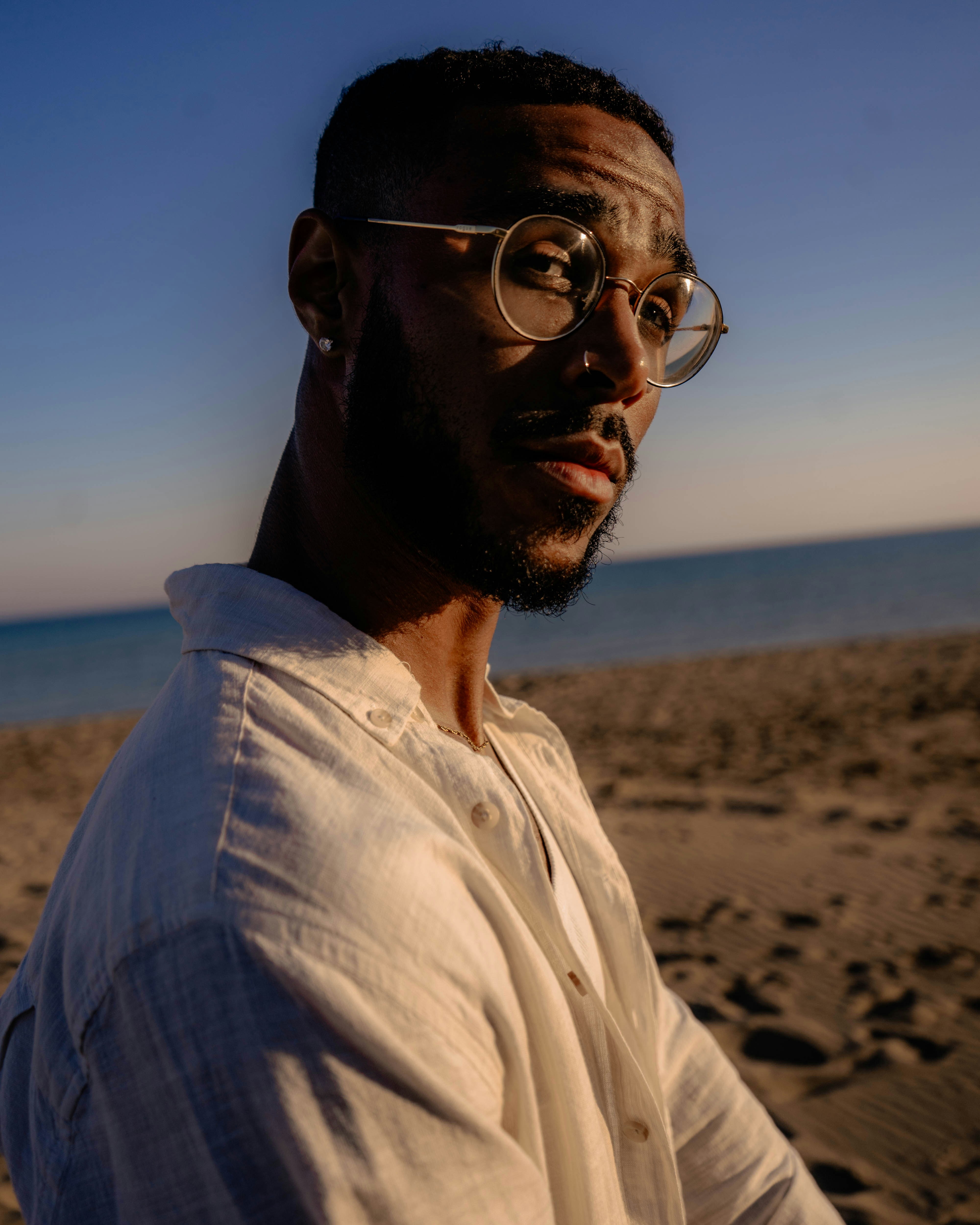 Man with glasses on beach at sunset