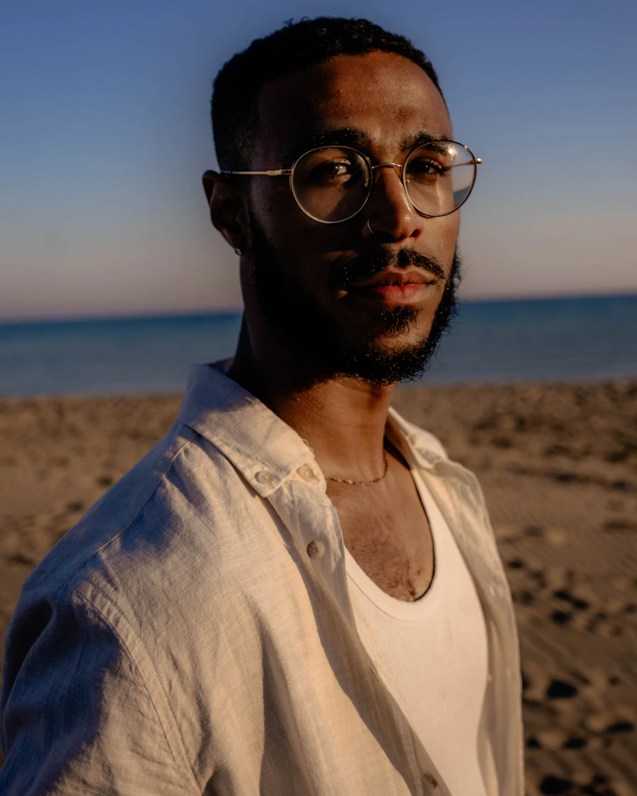 Bearded man in a linen shirt on the beach at dusk wearing a fine gold chain