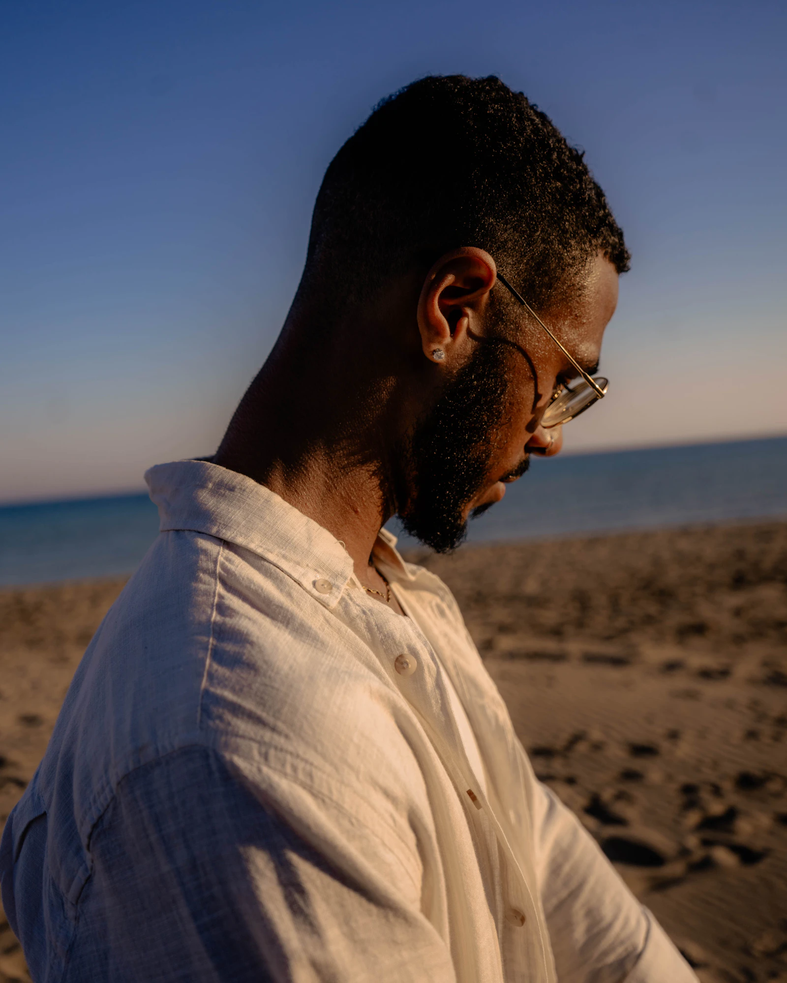Man in a white shirt walking on the beach at sunset