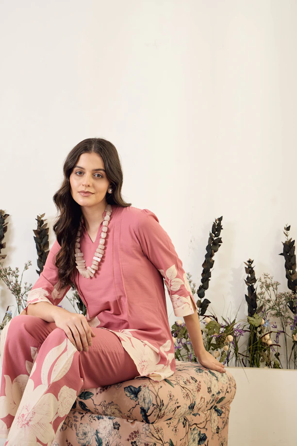 Woman in pink floral outfit sitting on patterned stool