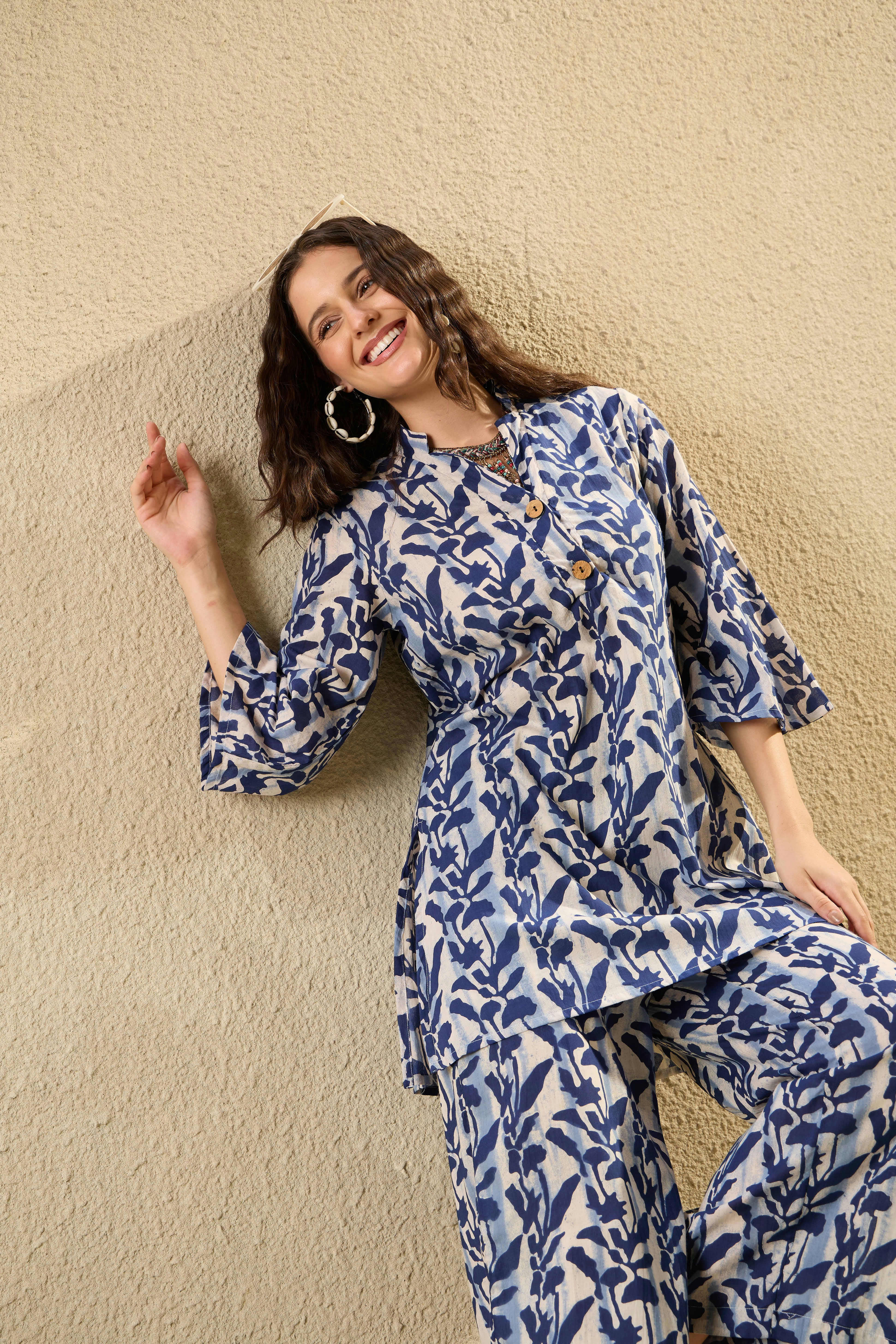 A woman in a blue and white patterned outfit smiles.