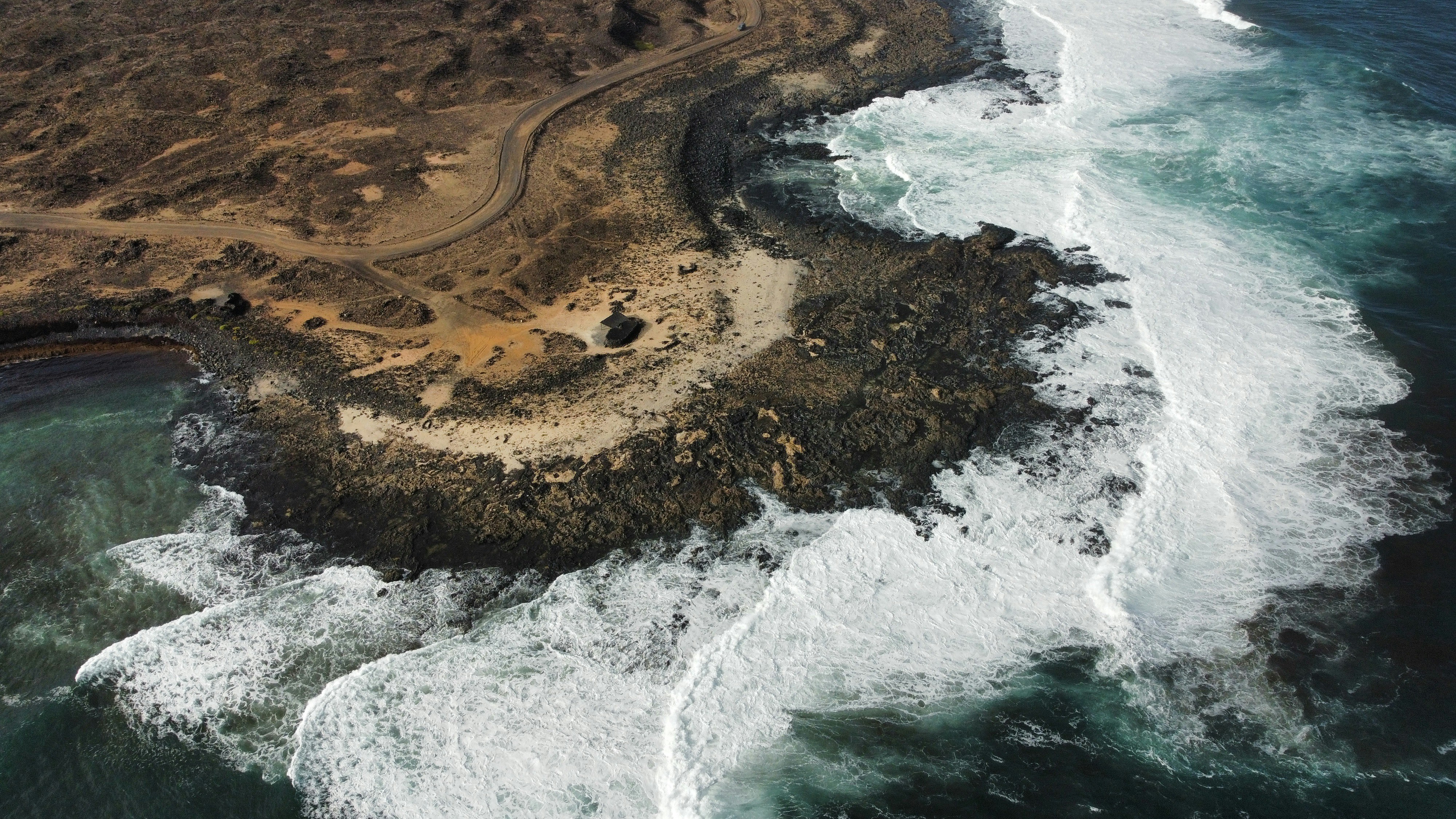 Waves crash on a rocky coastline under a cloudy sky