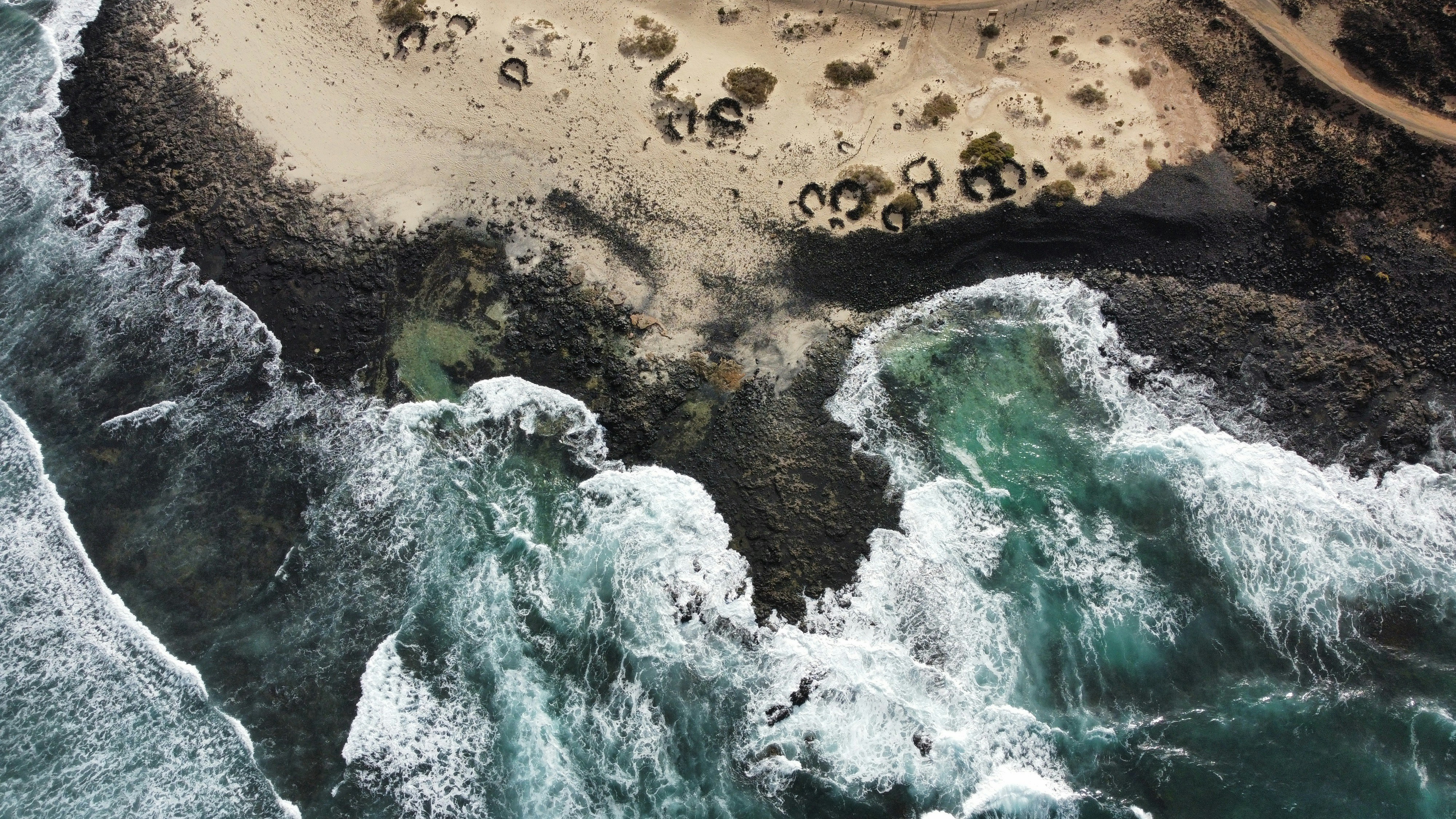 Aerial view of ocean waves crashing on rocky shore.