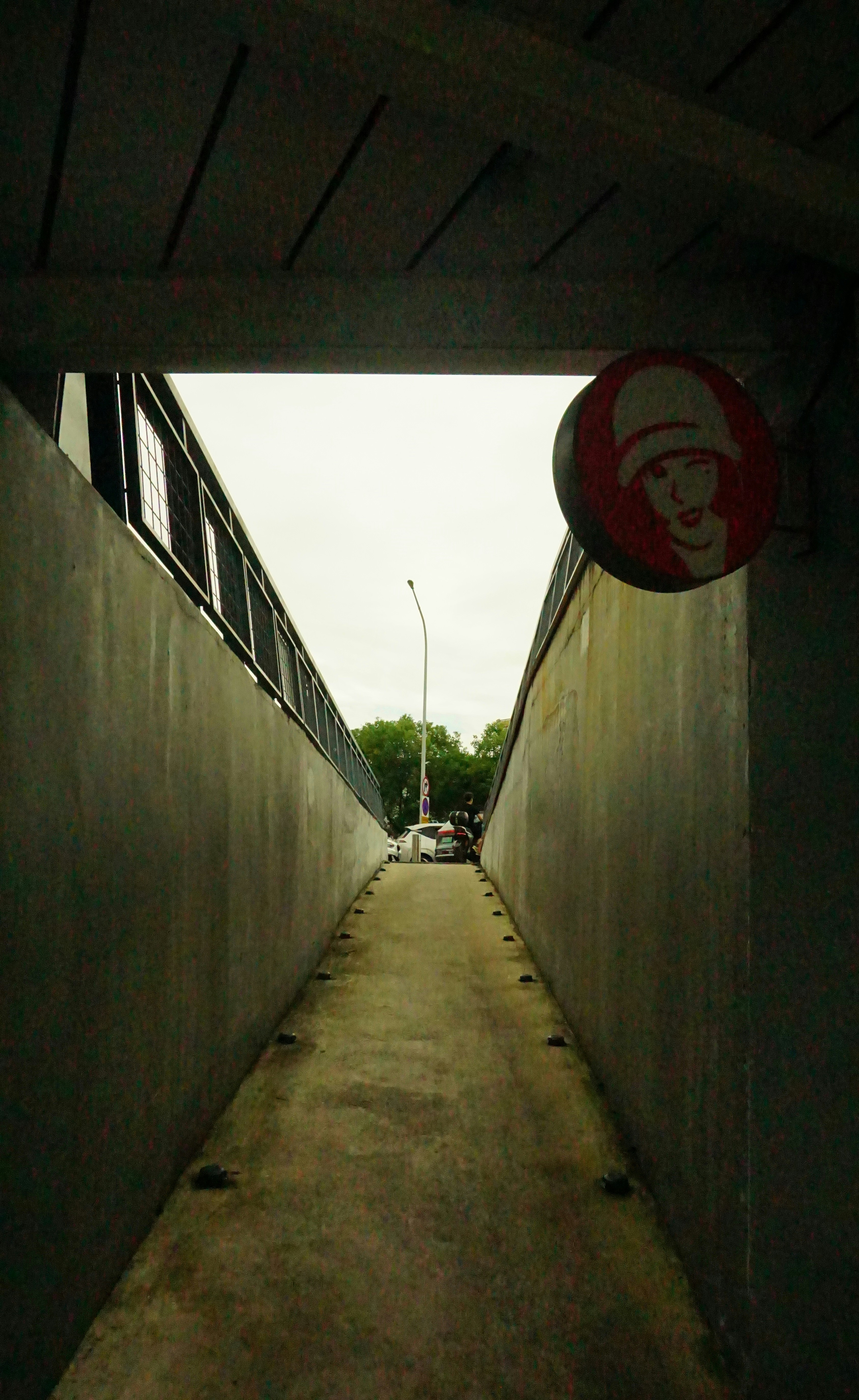 A pathway between concrete walls with a sign