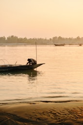 Fisherman on a boat at sunrise on the river.