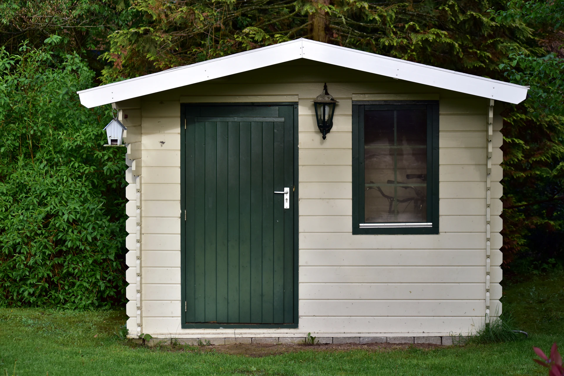 A small wooden shed with a green door and window.