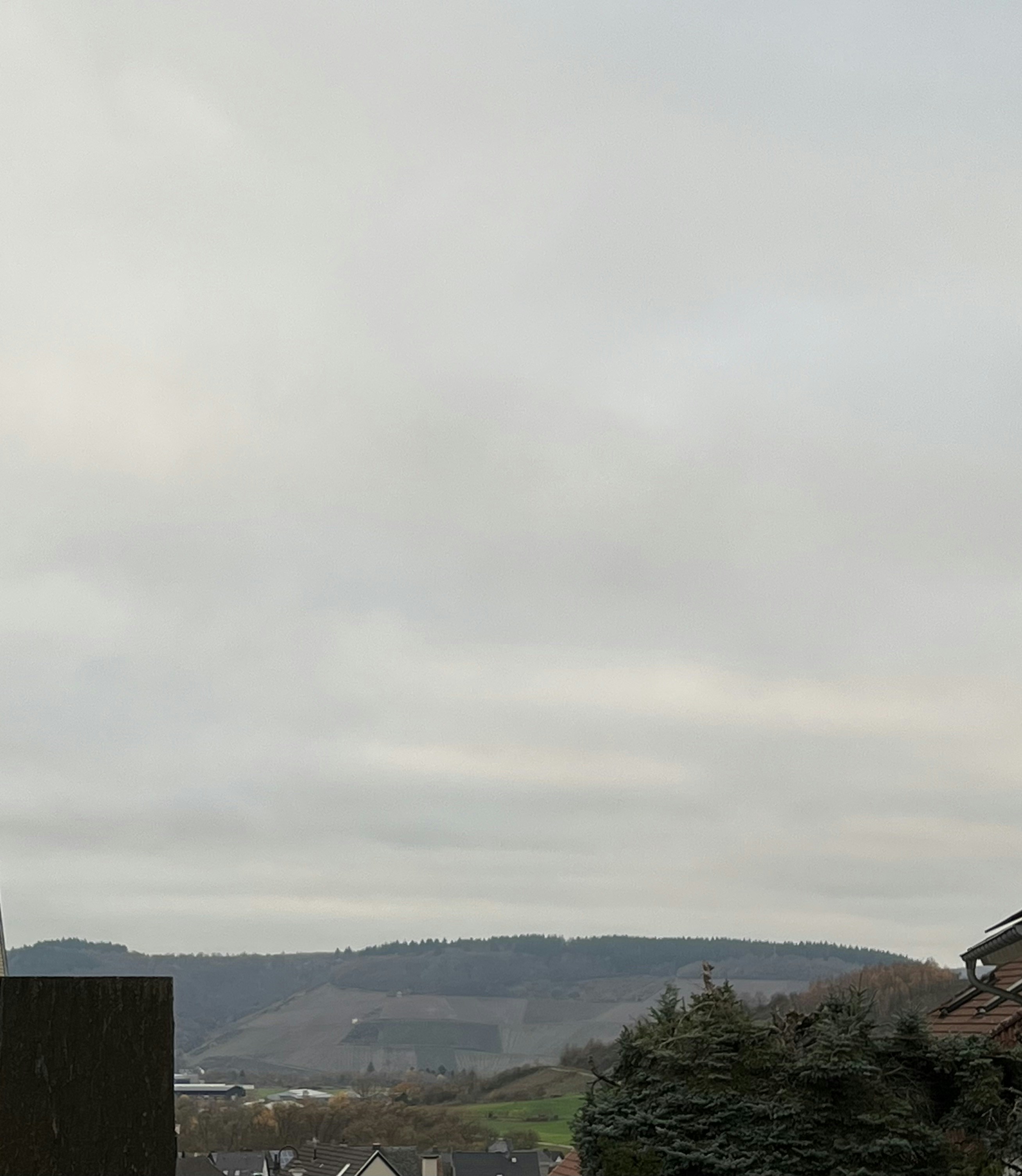 Overcast sky above rolling hills and village.
