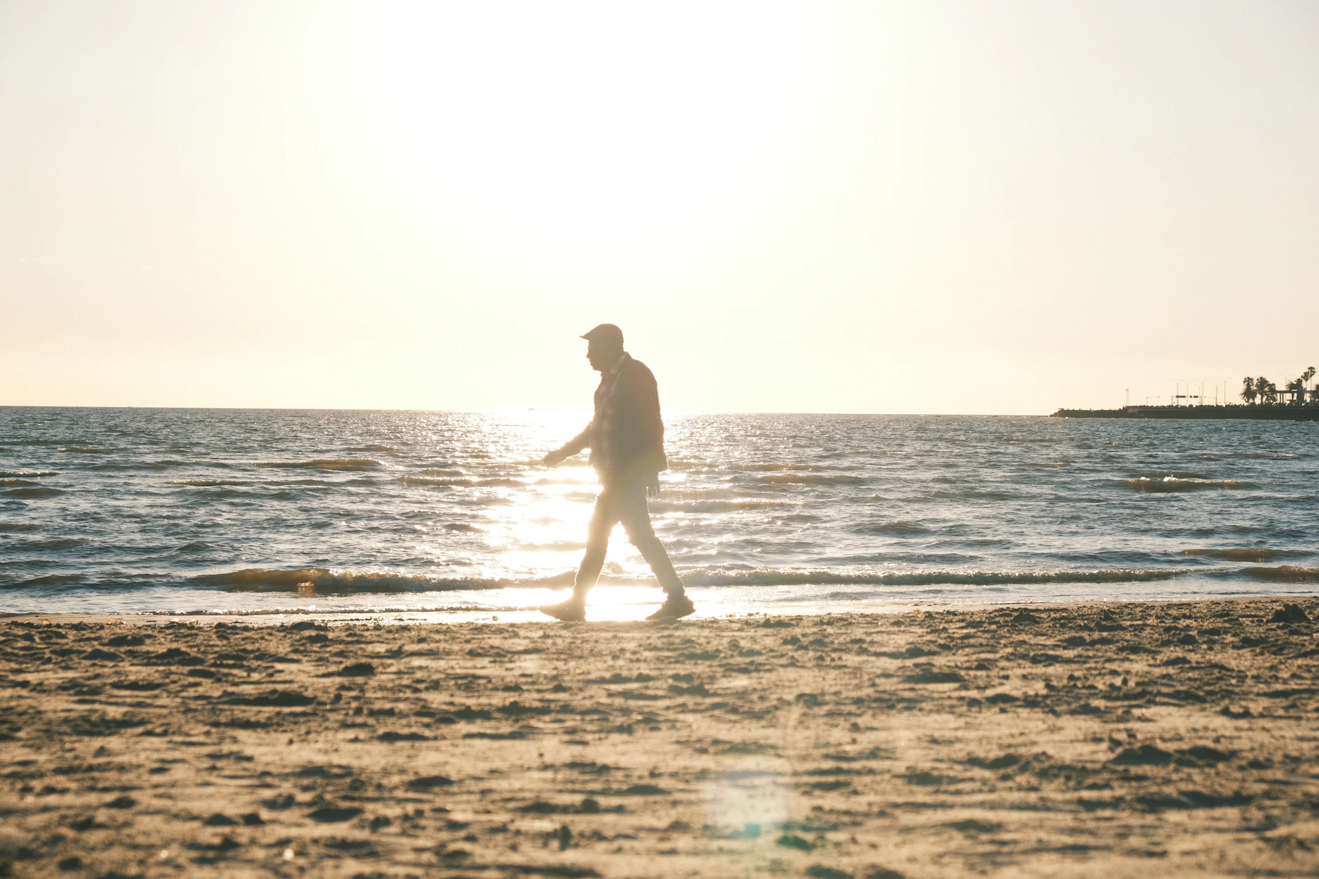 Man walking on a sandy beach at sunset