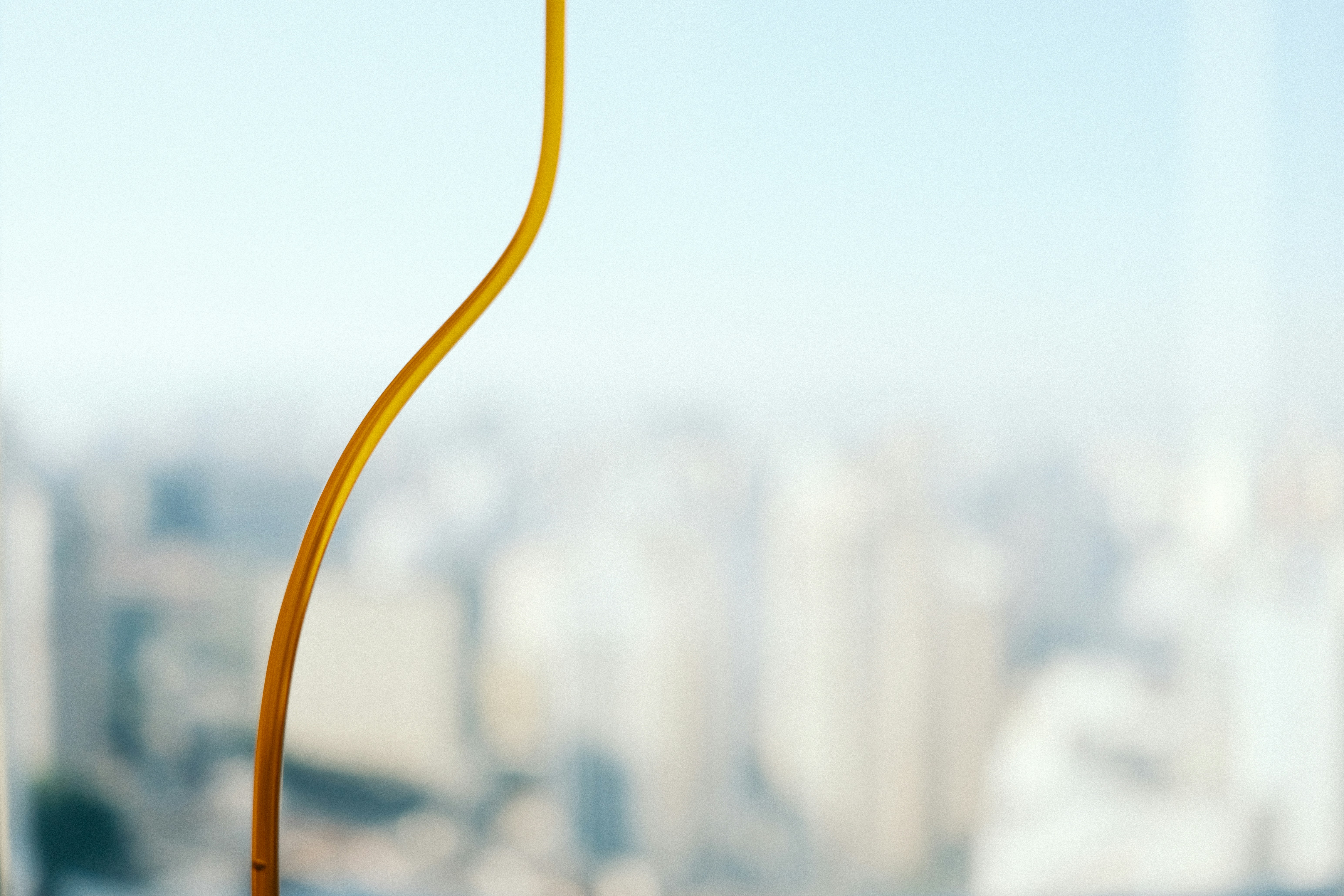 A thin yellow line curves against a blurred cityscape.