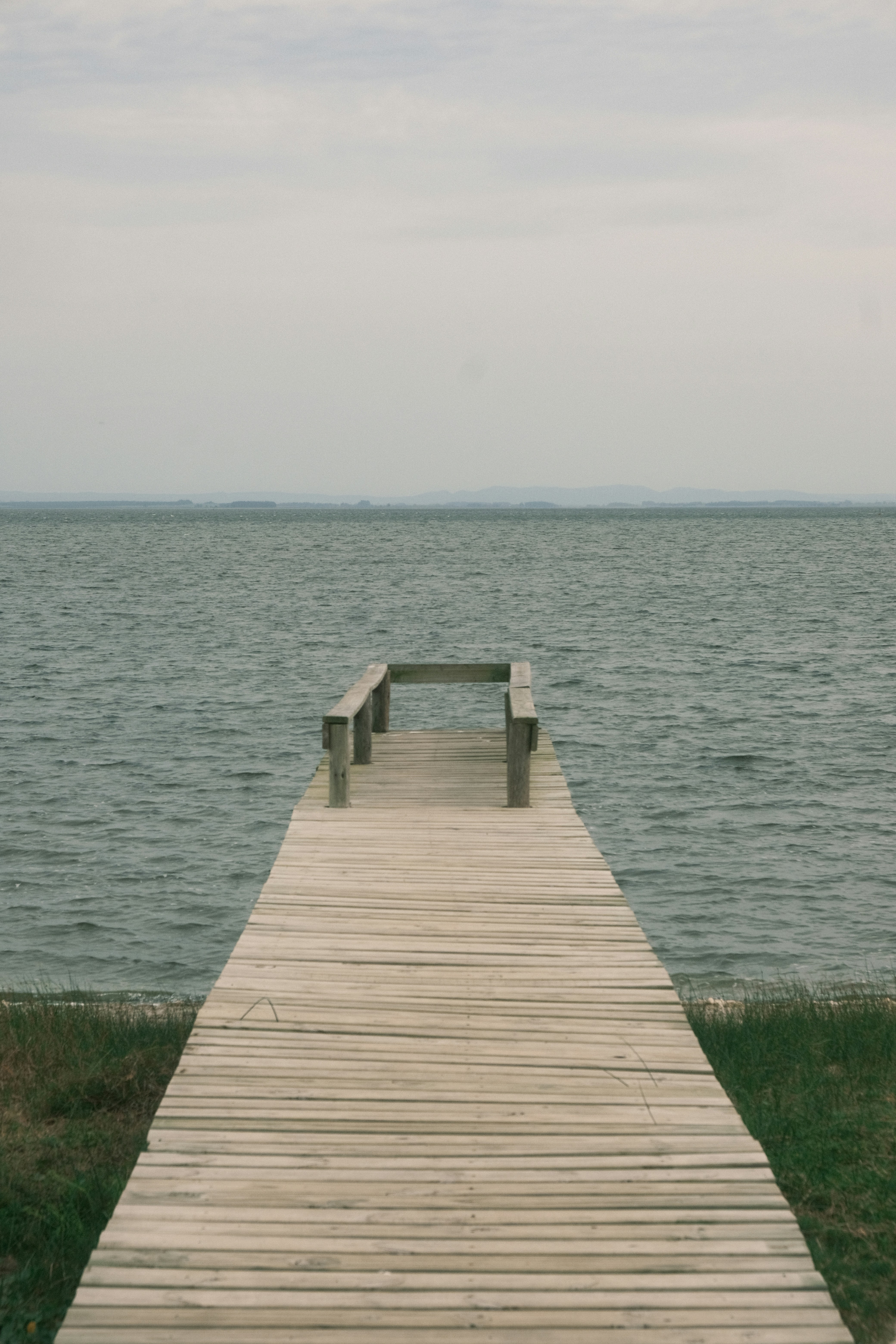 Wooden pier extending into a calm, gray ocean.