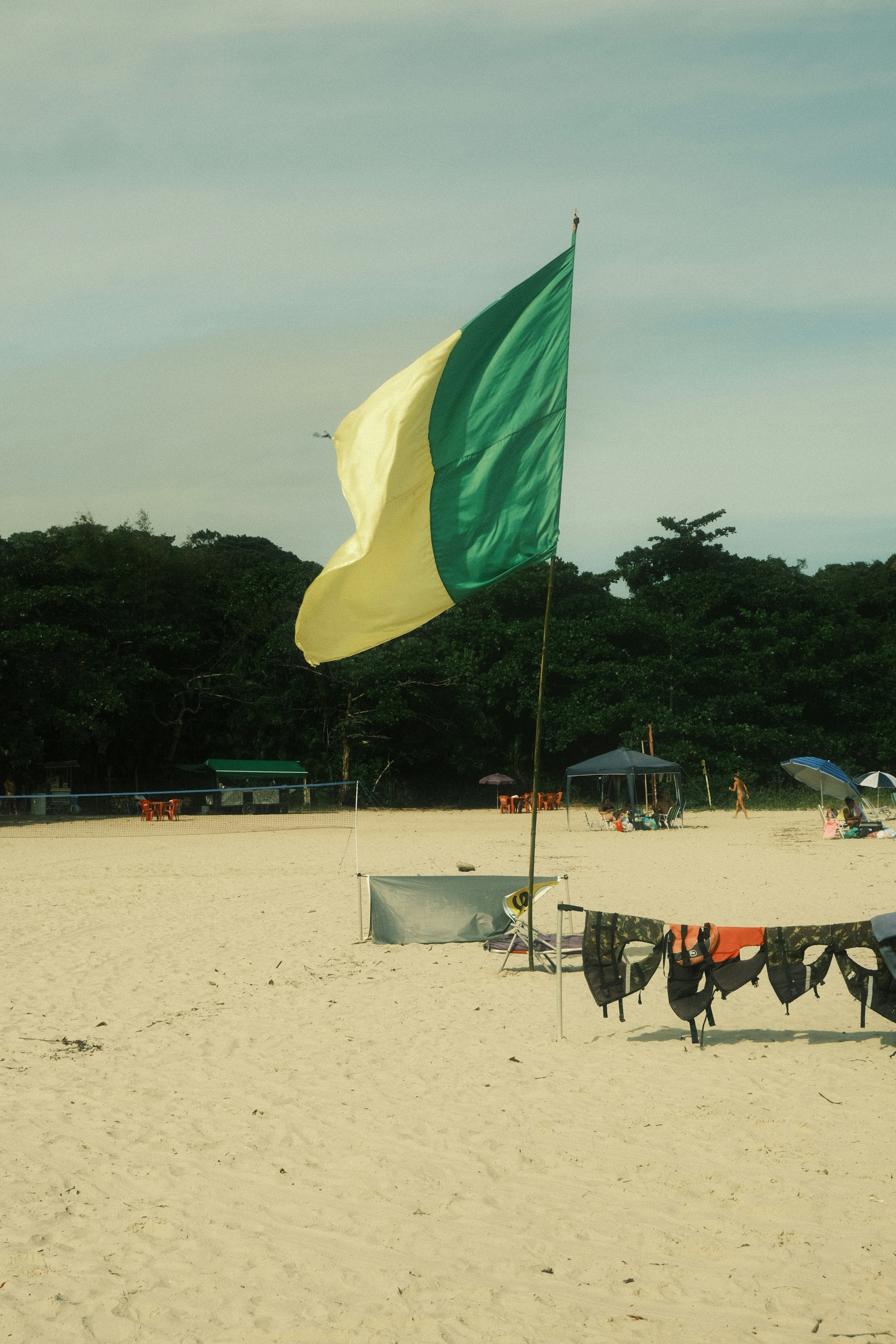 A green and yellow flag on a sandy beach.