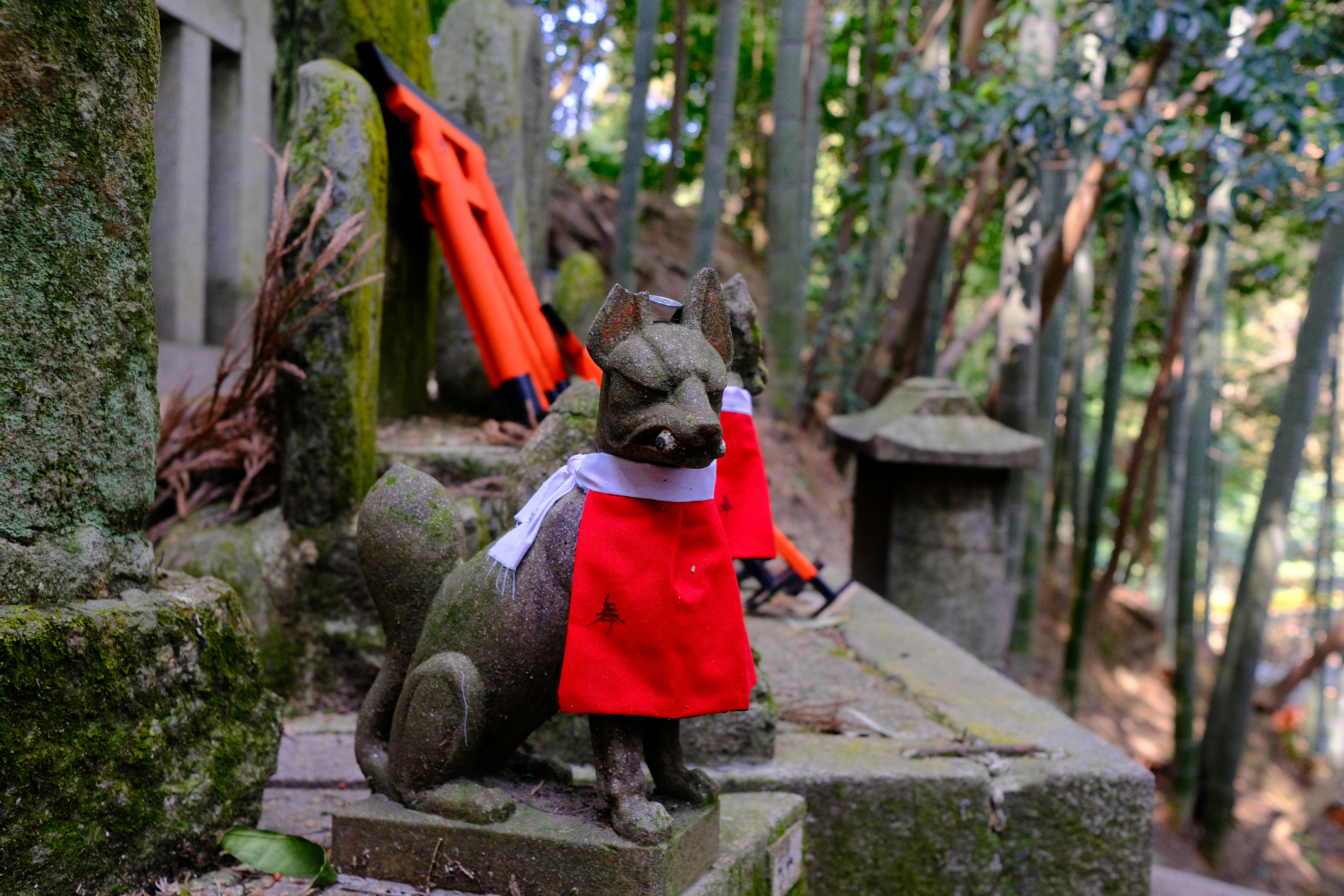 Steinfuchsstatue mit rotem Lätzchen im Schrein