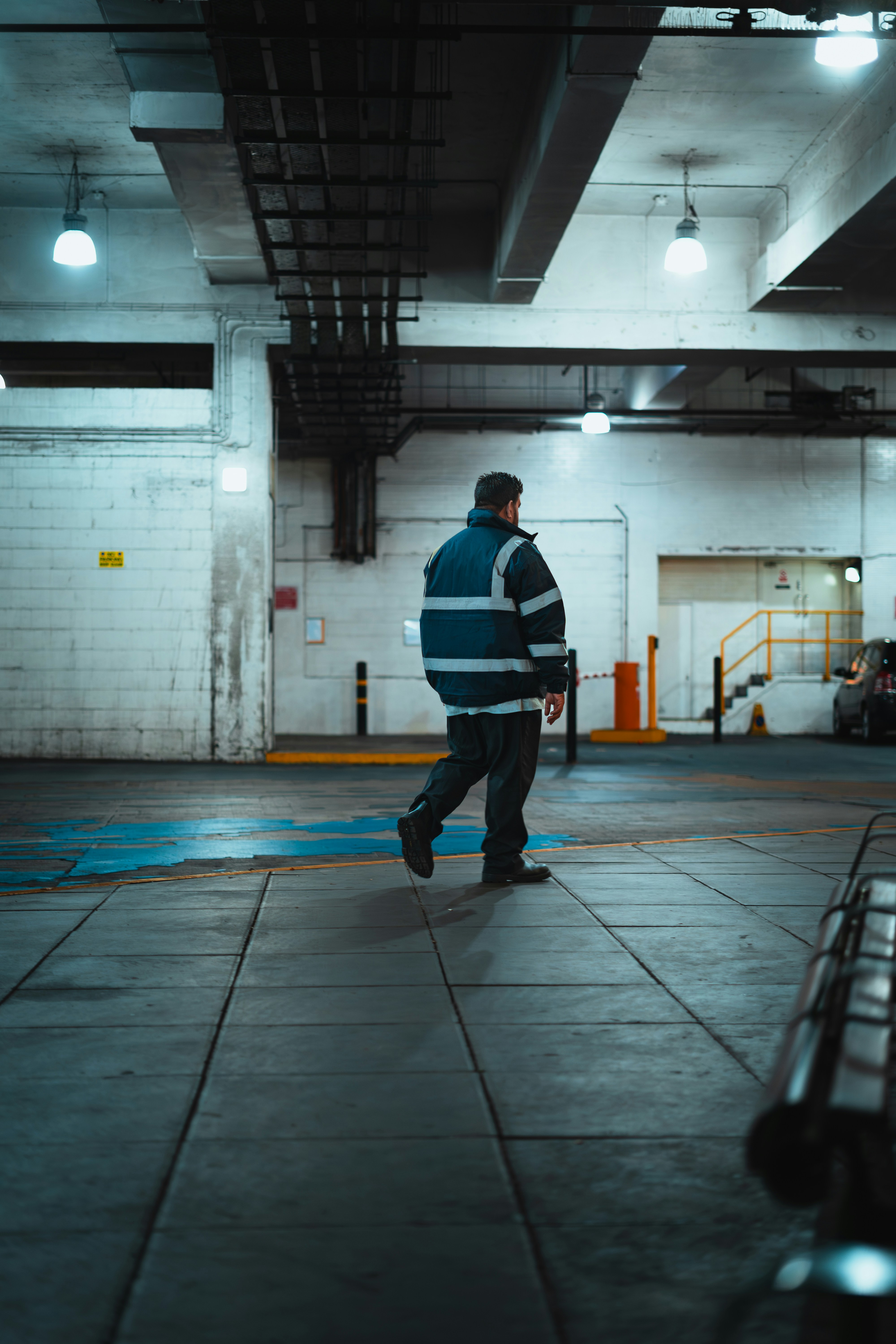 Mann in reflektierender Jacke geht im Industriegebäude.
