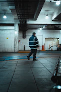Man in reflective jacket walks in industrial building.