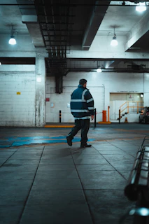 Man in reflective jacket walks in industrial building.