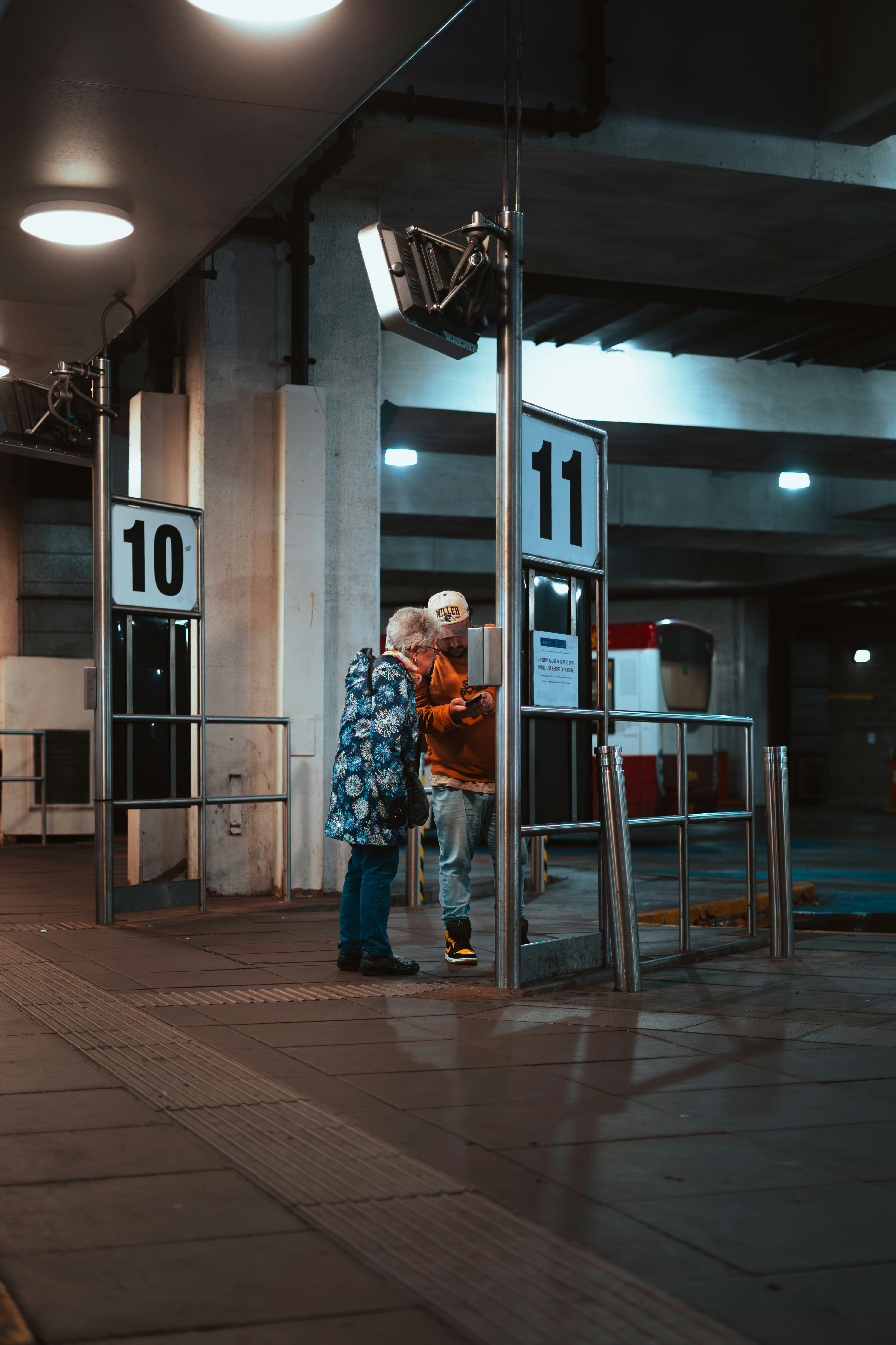 Two people looking at a ticket machine at a station.