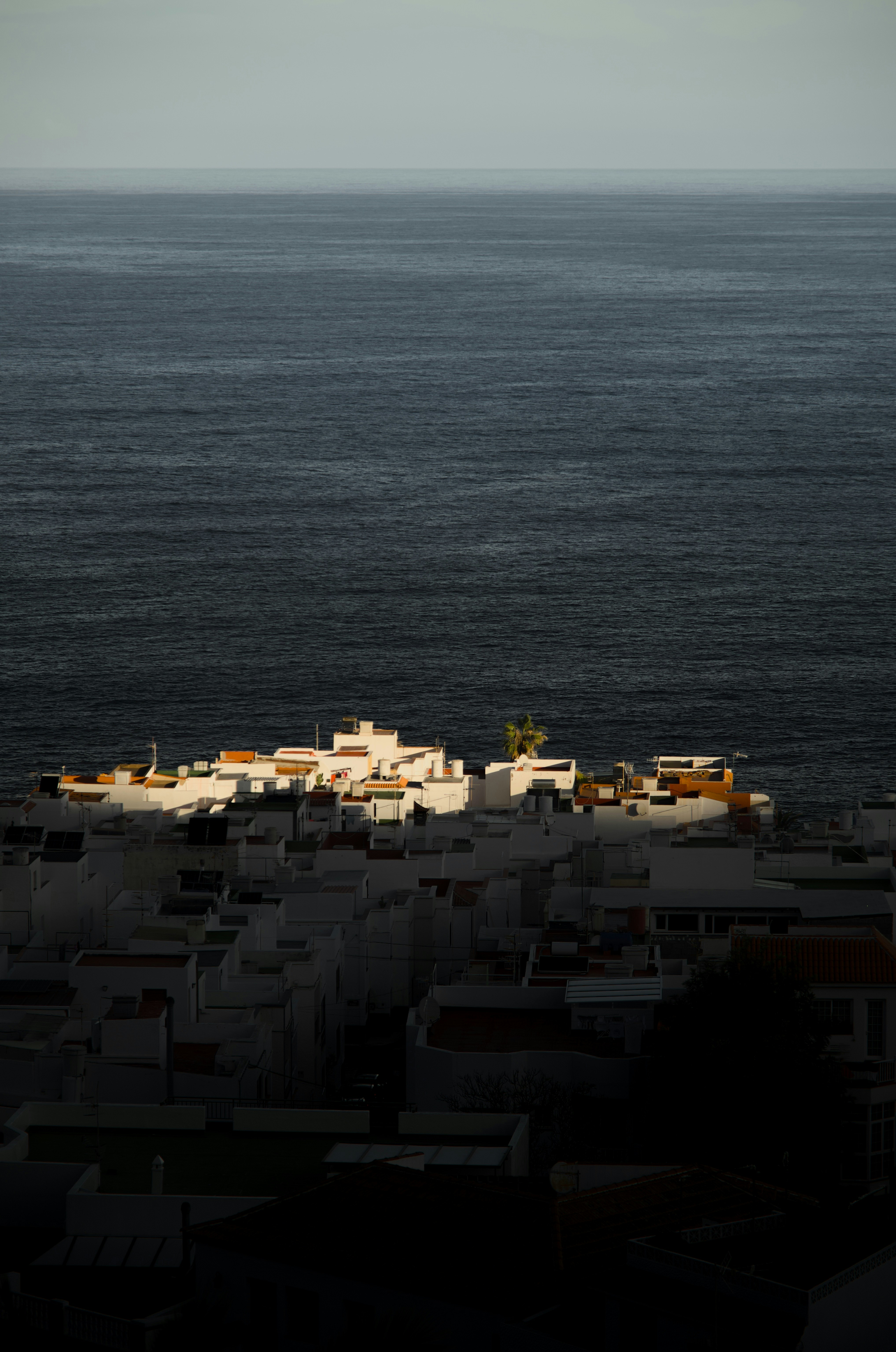 White buildings illuminated by sunlight near the ocean.