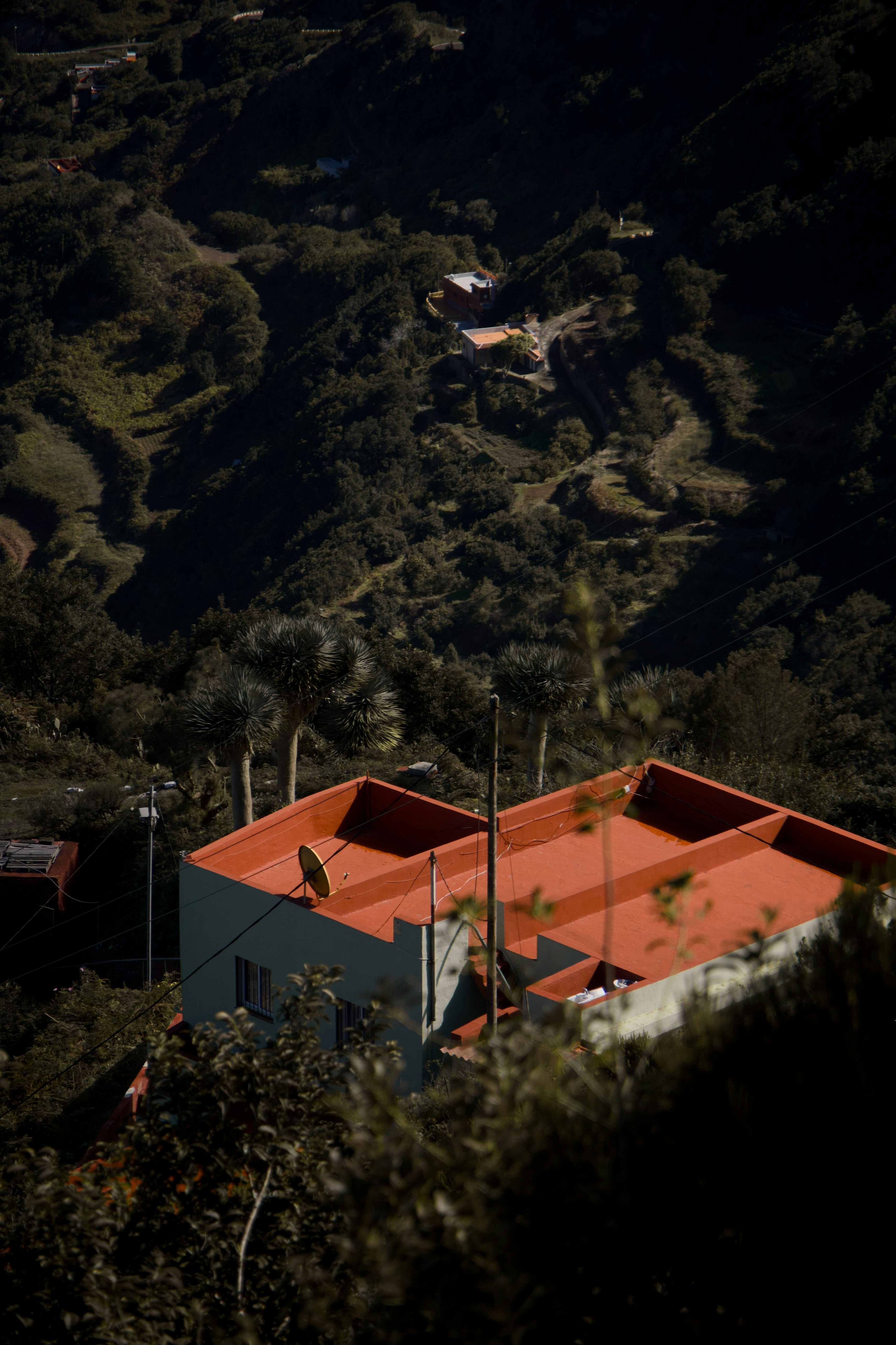 Une maison au toit rouge nichée dans des collines vertes.