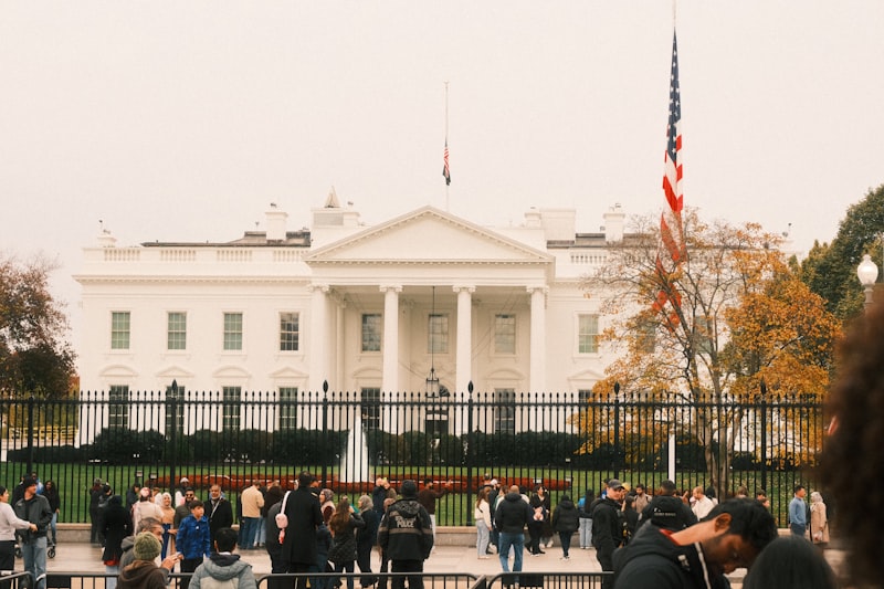 The White House with an American flag and visitors gathered outside