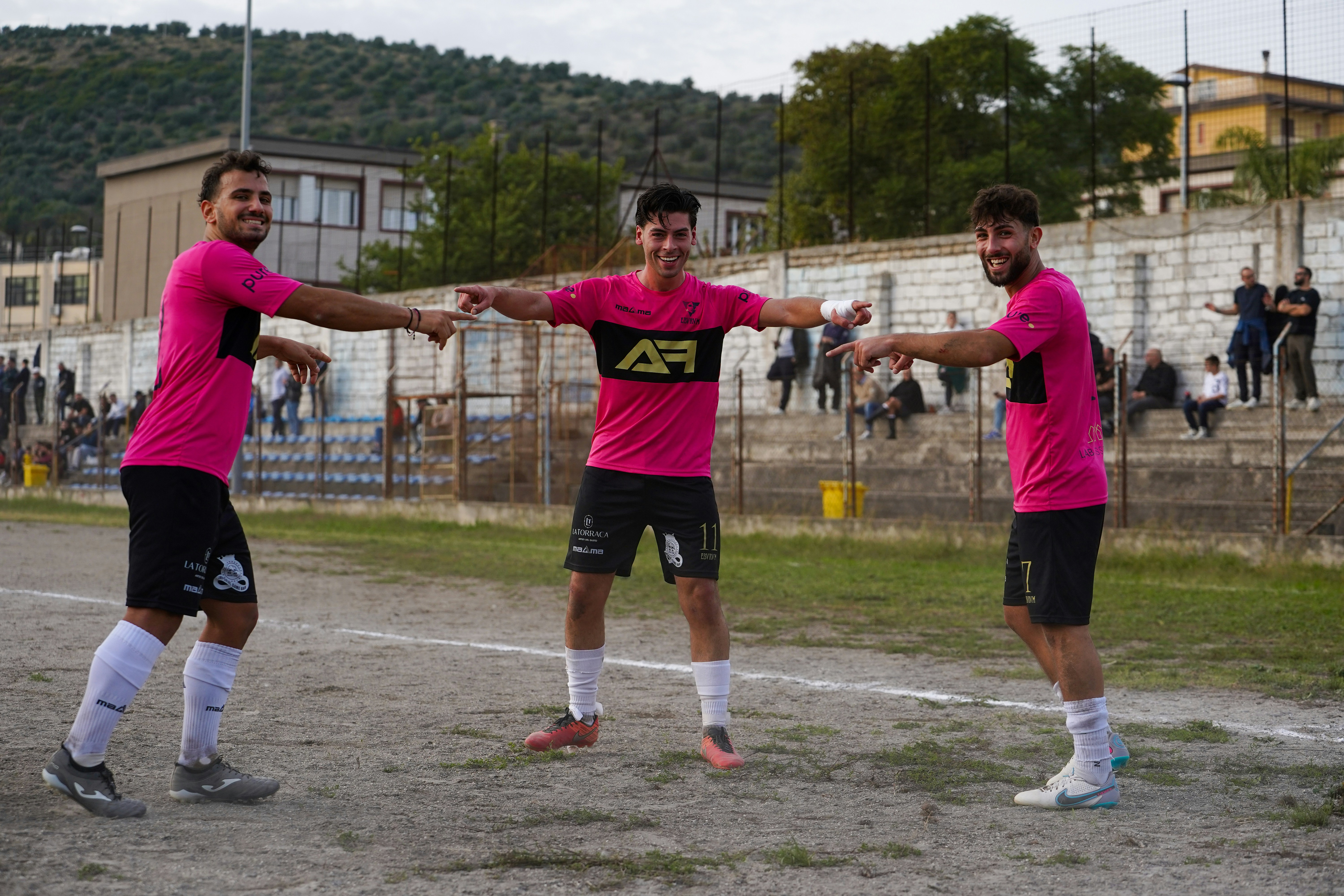 Three soccer players in pink jerseys celebrating together