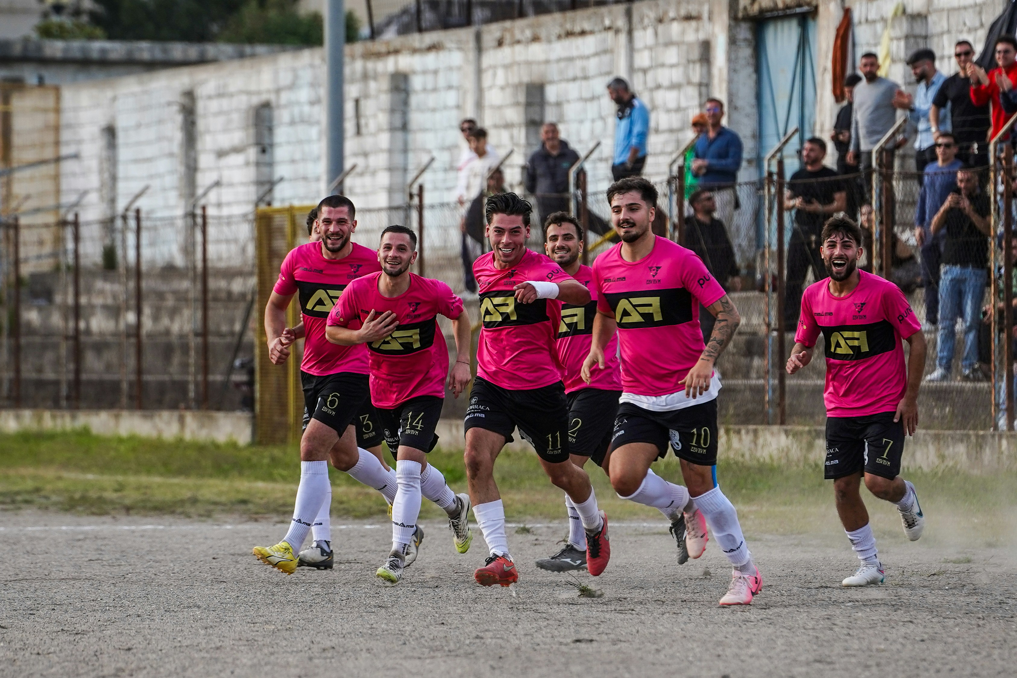Football players in pink jerseys celebrate on field.