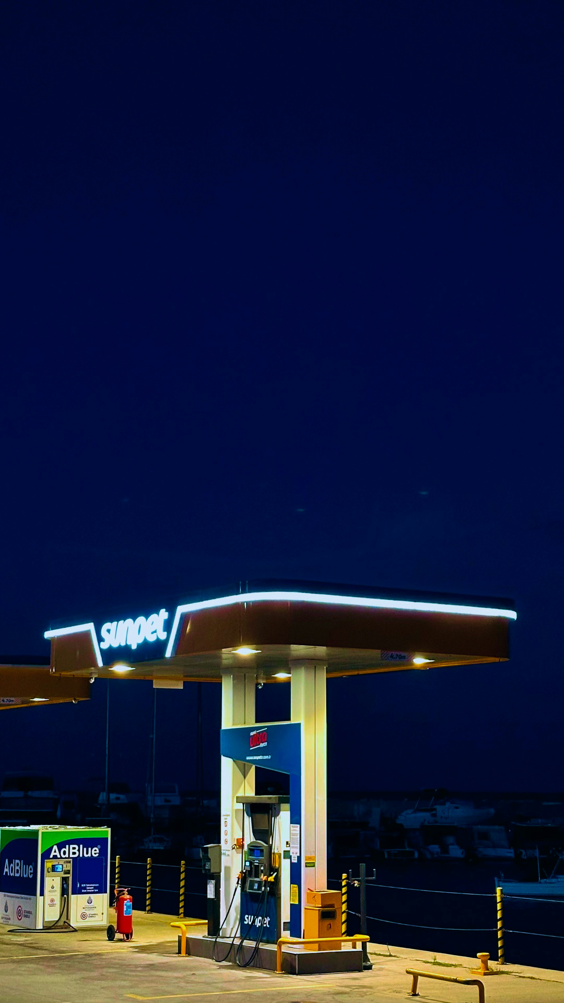 Station-service éclairée la nuit sous un ciel sombre