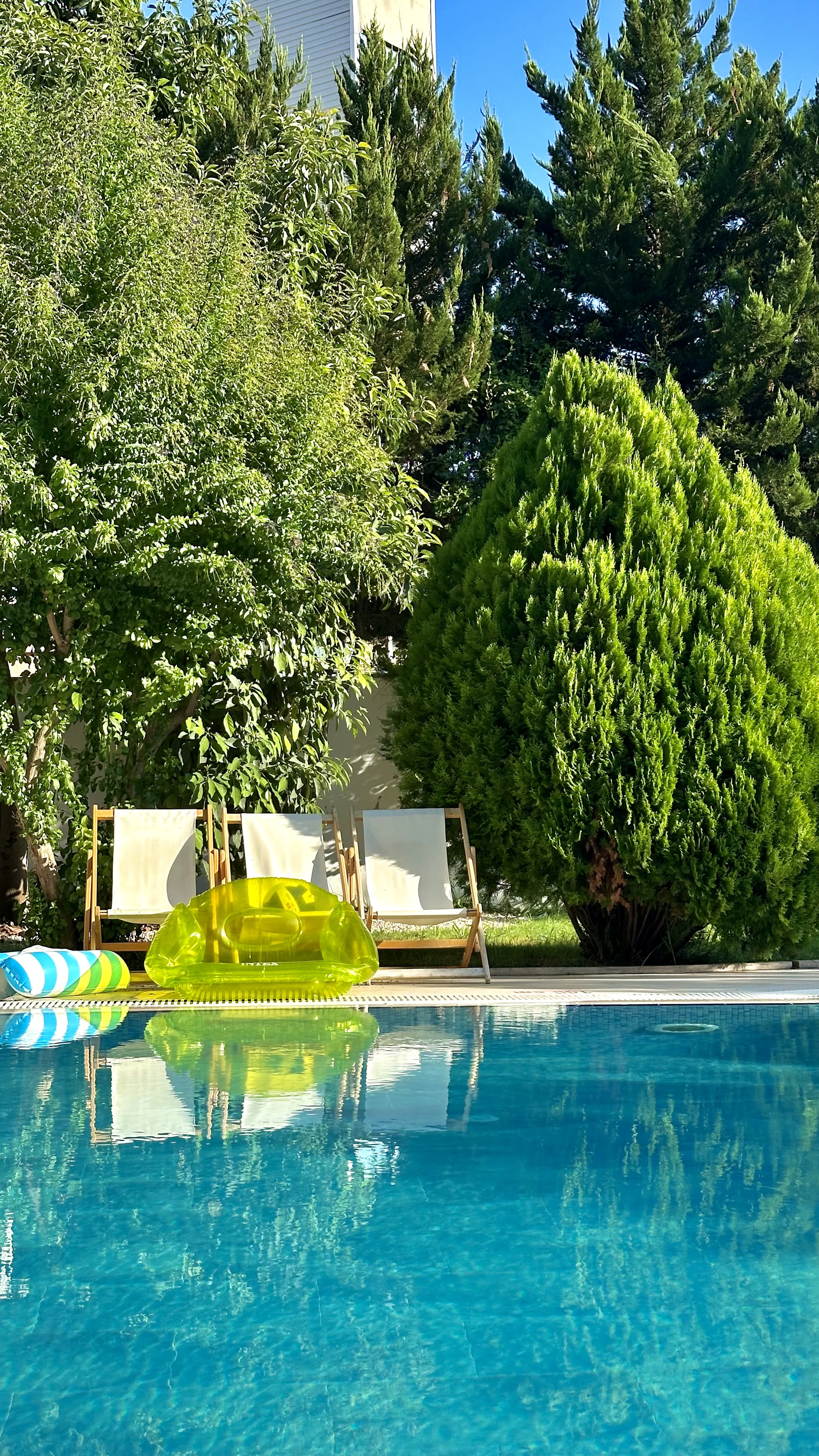 Two lounge chairs by a pool with inflatable toys.