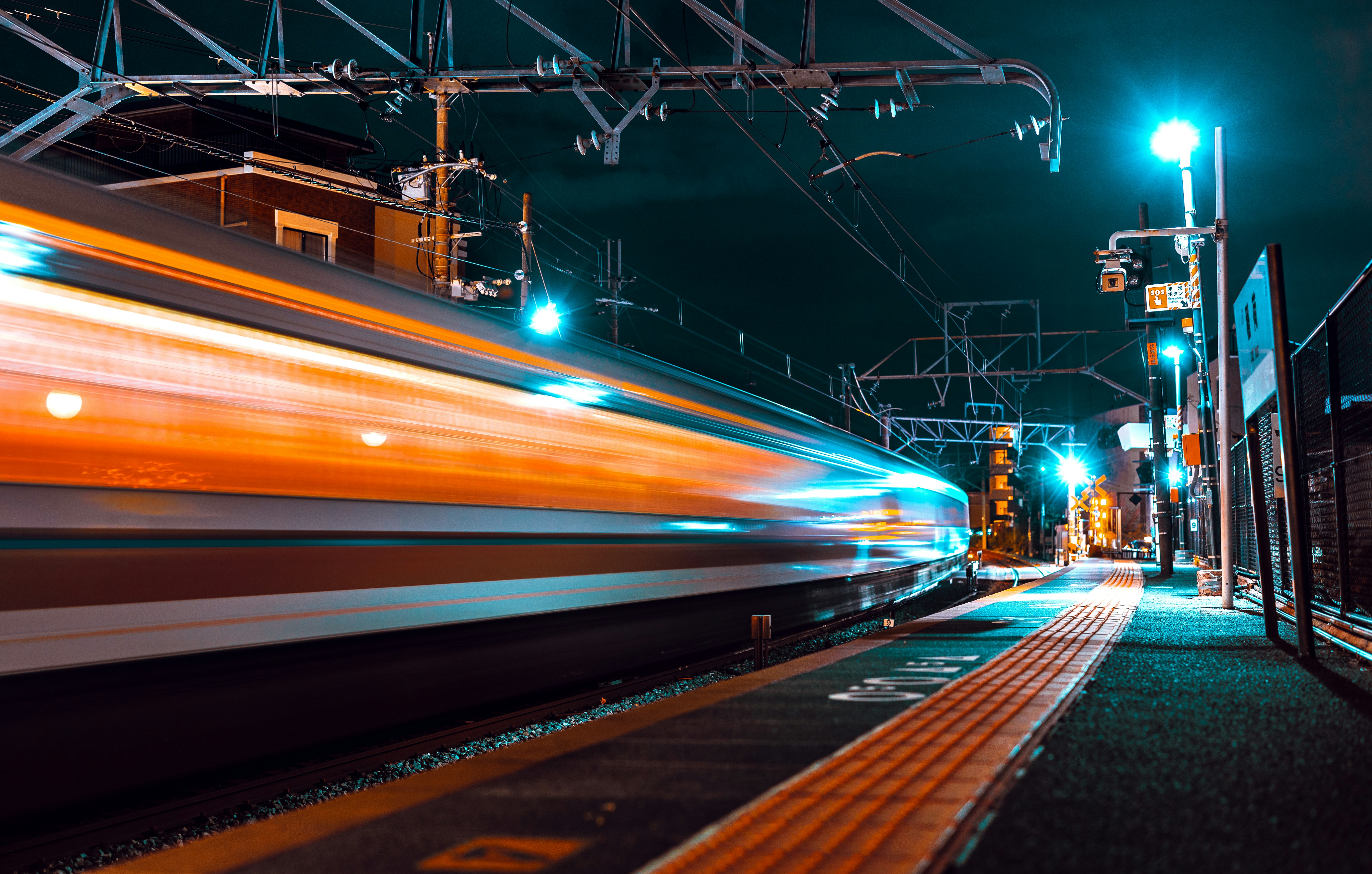 A train speeds through a station at night