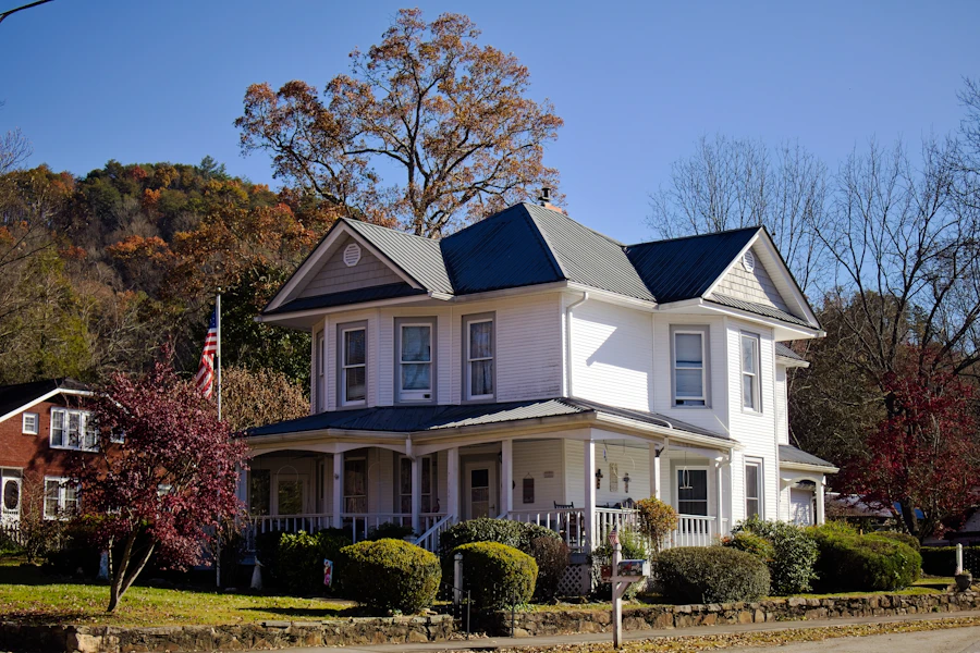 White two-storey house with a wide wraparound front porch and mature trees — the Douglasville home.