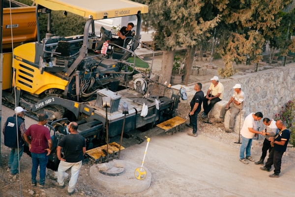 Paving crew operating asphalt machinery on a commercial site