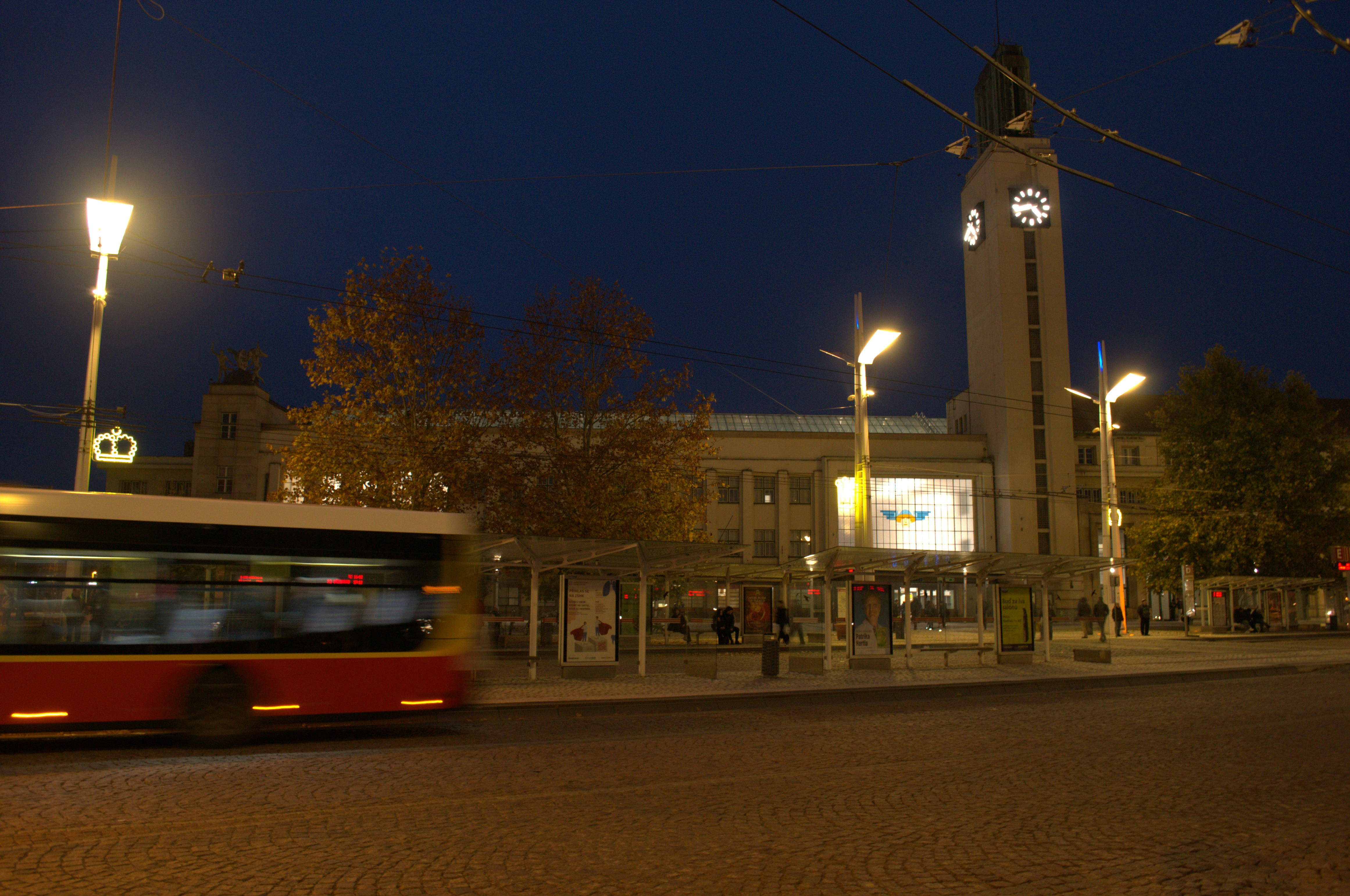Bus passes building with clock tower at night