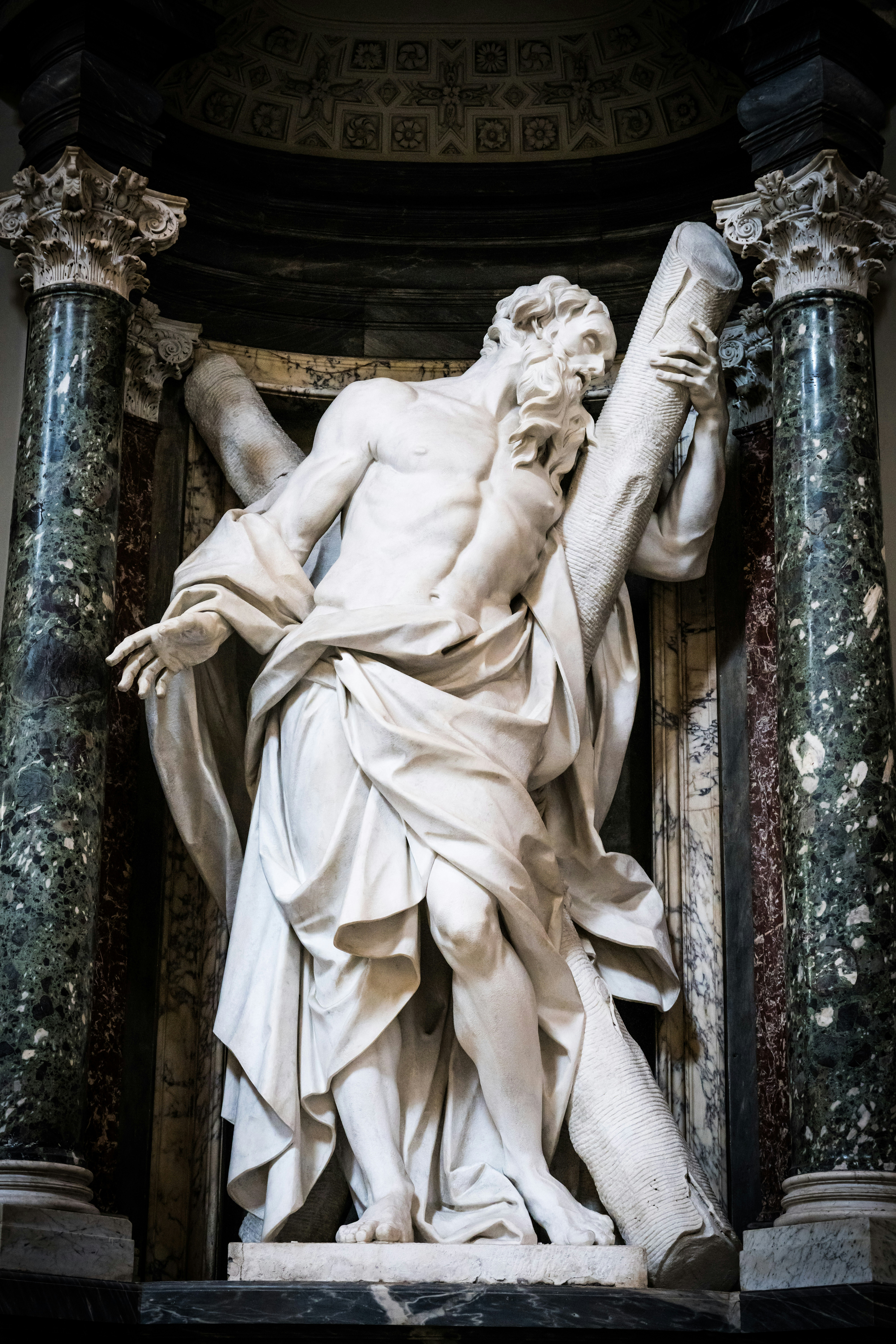 Marble sculpture of a man carrying a large cross