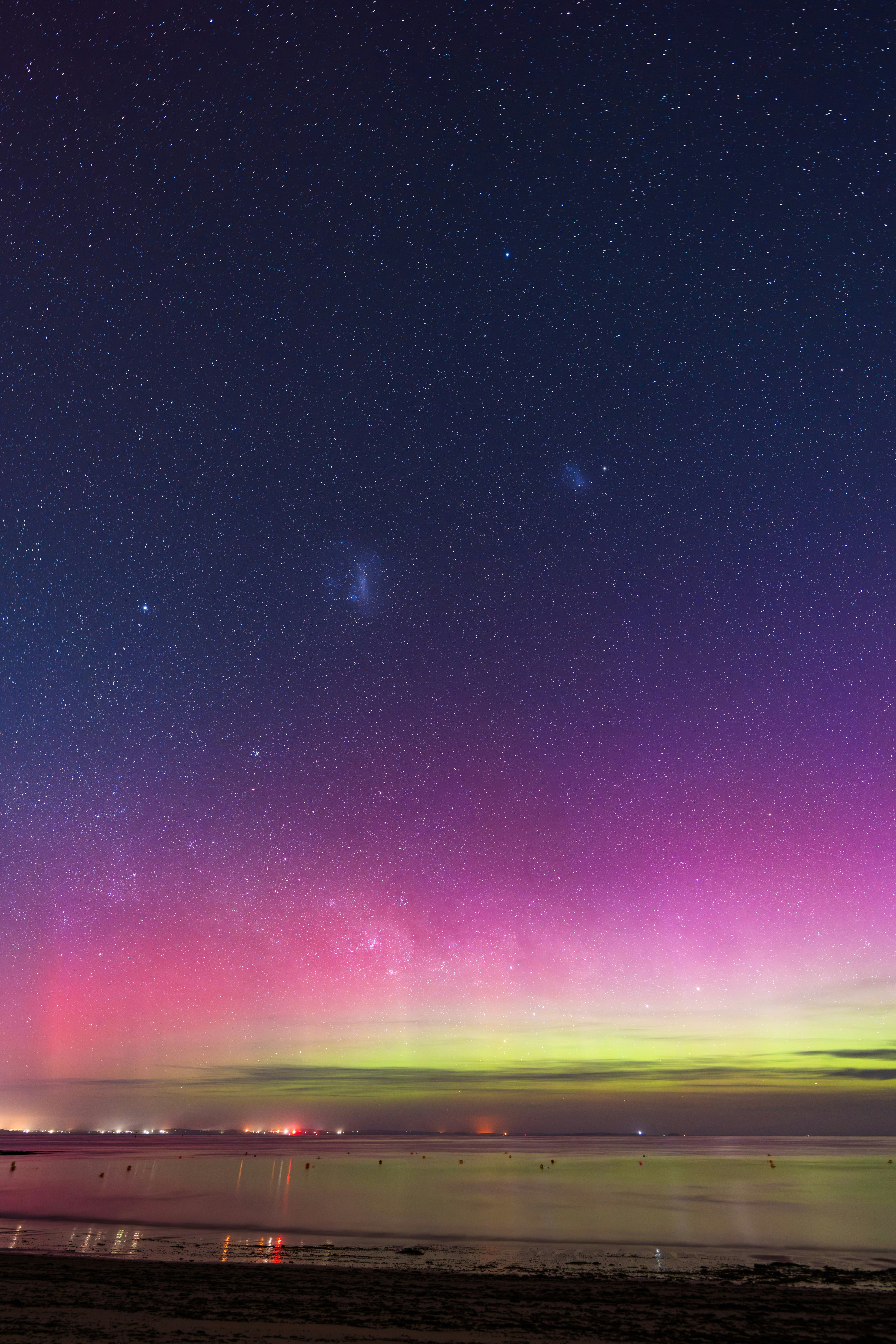 Aurore boréale au-dessus d’une ville côtière la nuit
