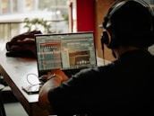 Person wearing headphones using laptop with audio software.