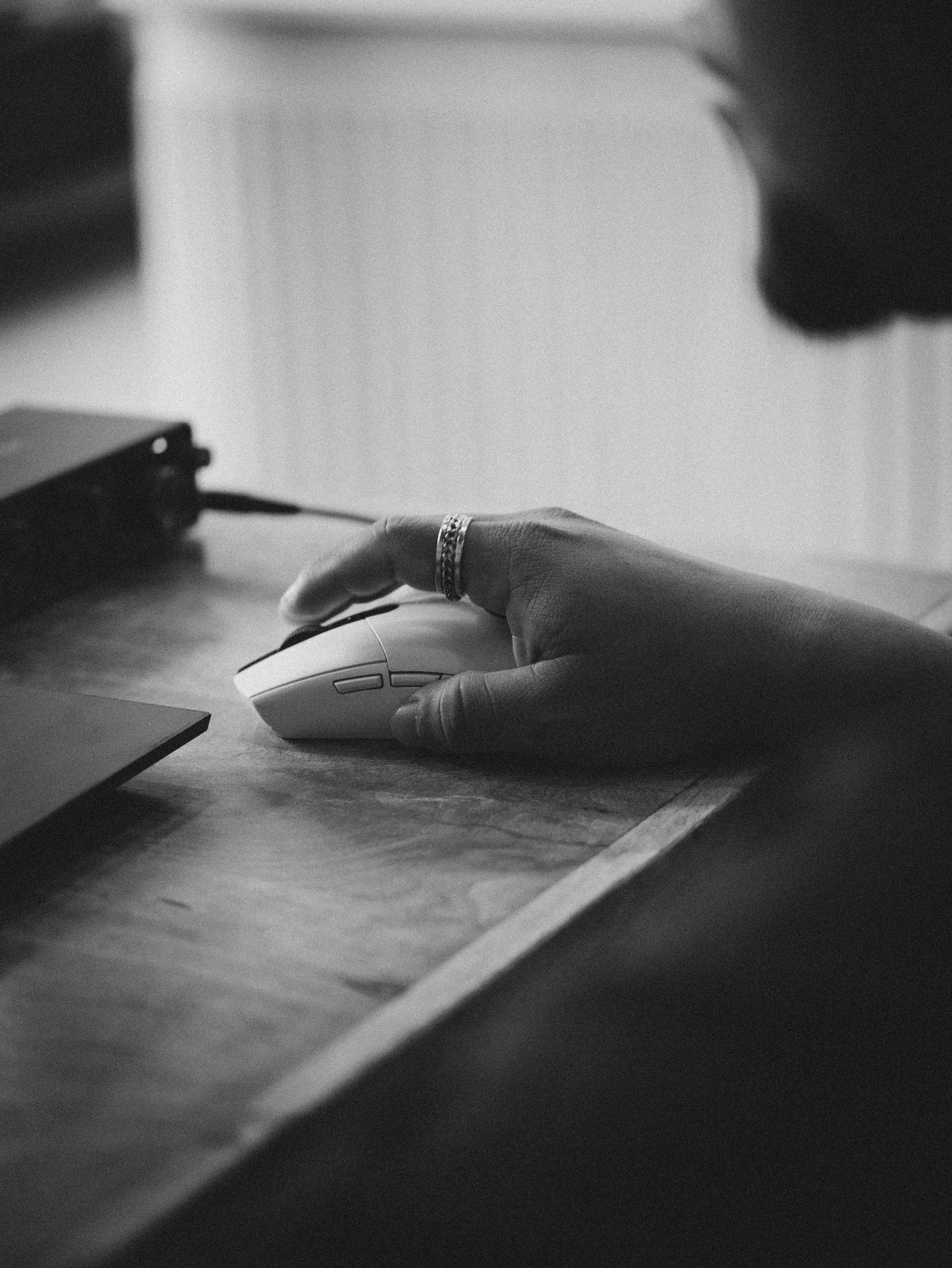 Person's hand using a computer mouse on a desk.