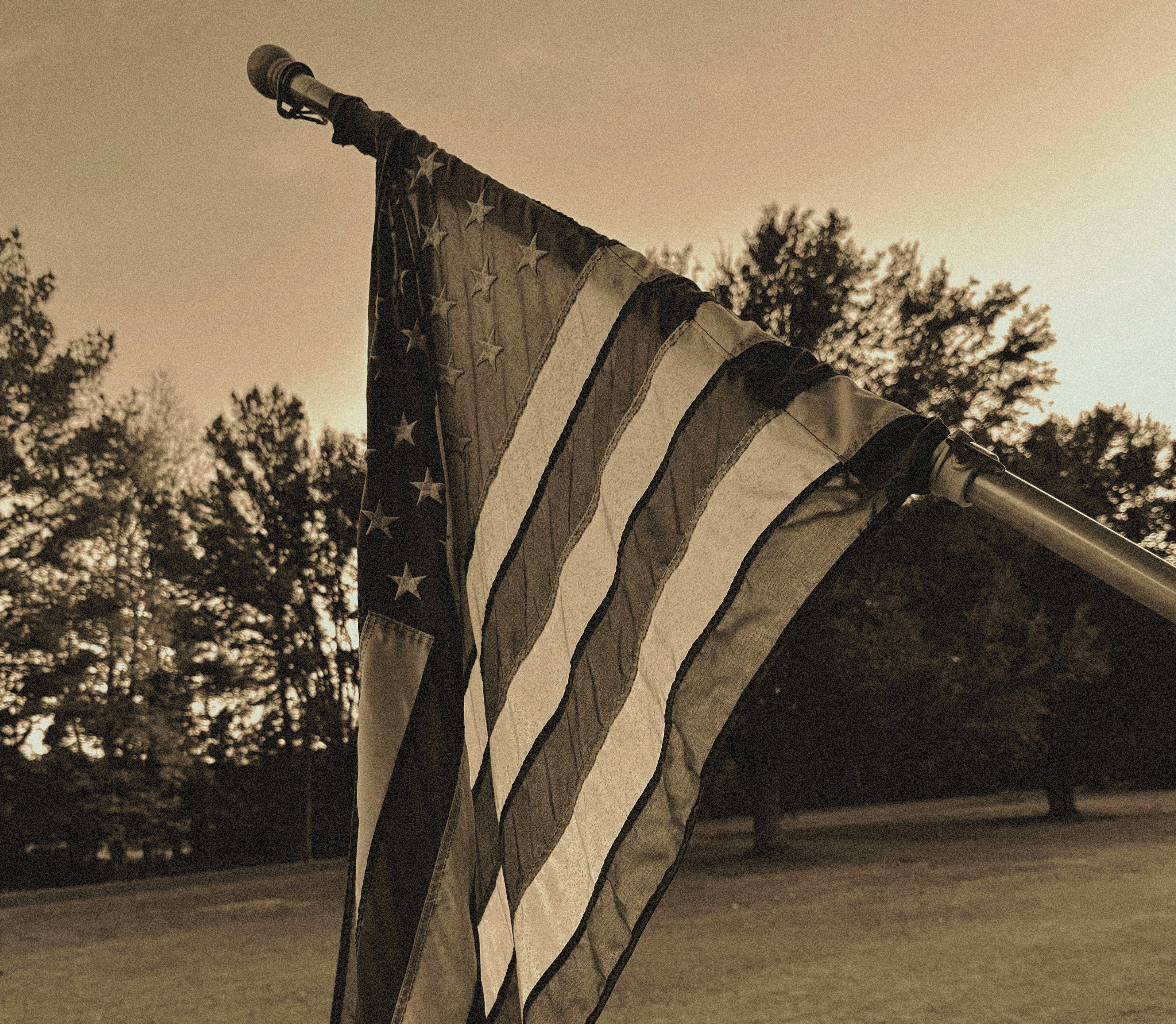 American flag waving on a pole with trees background