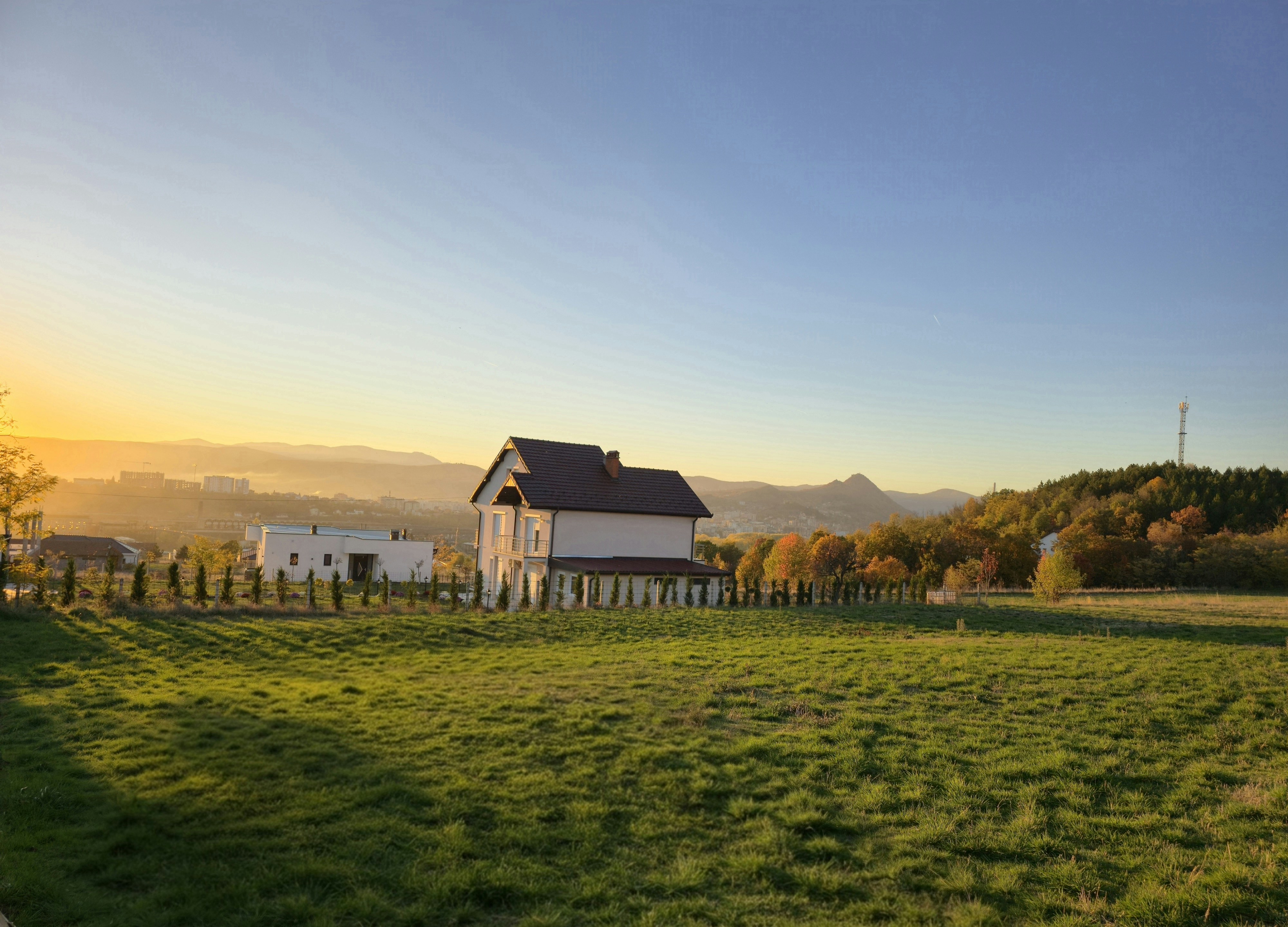 House on a hill at sunset with grassy field.